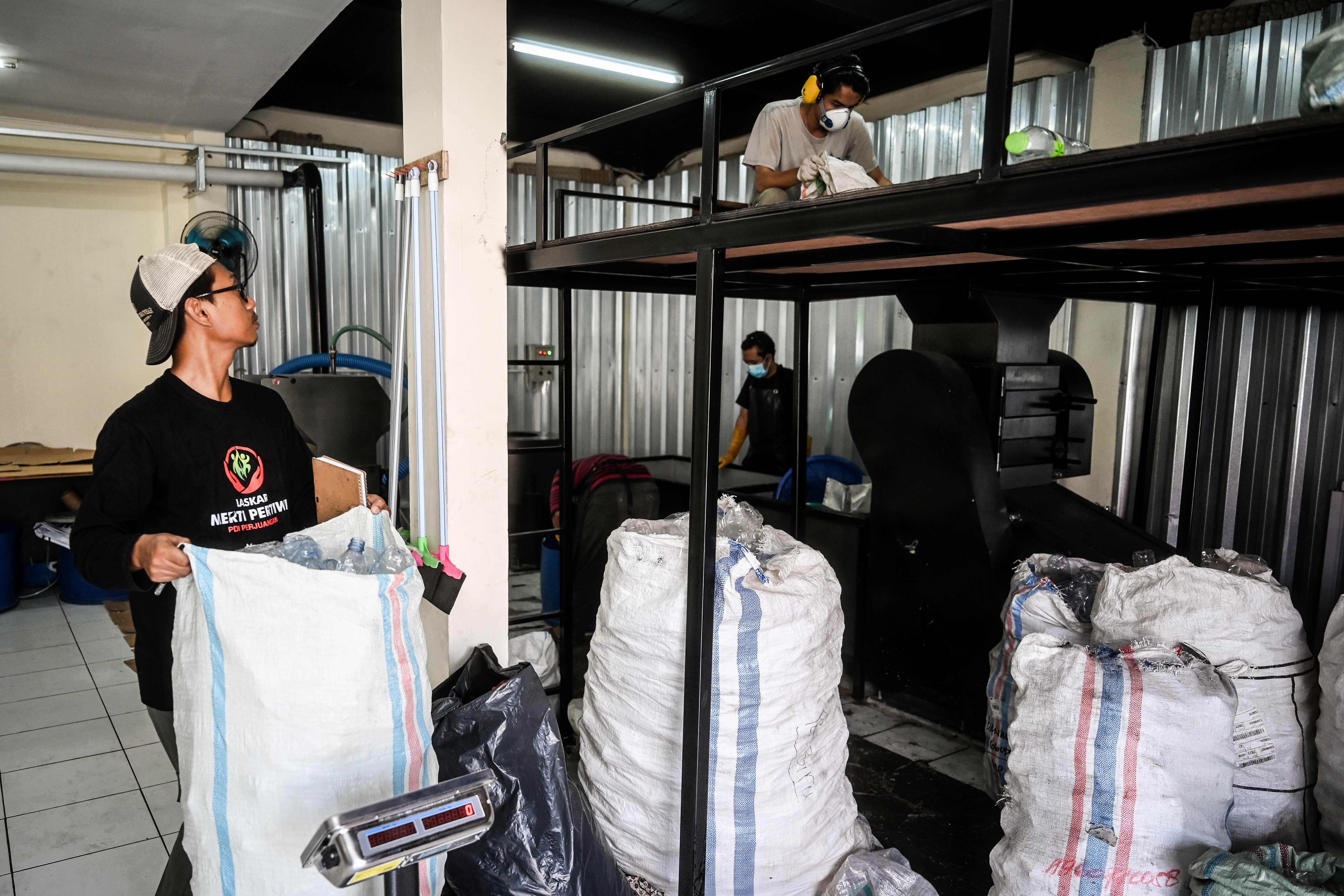 Pekerja membawa karung berisi sampah plastik untuk didaur ulang menjadi bahan kerajinan di rumah produksi Bank Sampah Budi Luhur, Tangerang.