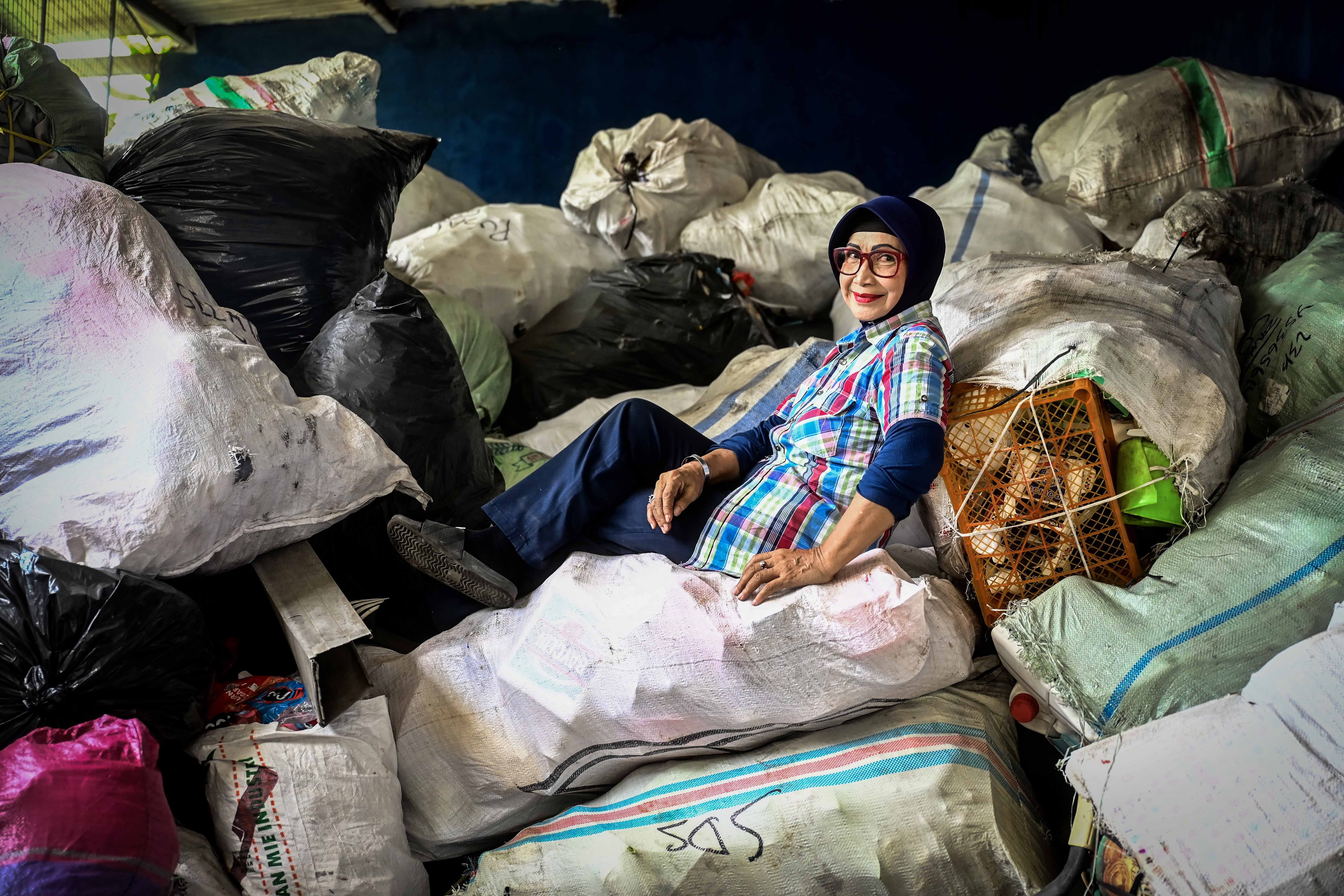 Umi Tutik Asmawi berpose di atas tumpukan karung sampah di Bank Sampah Budi Luhur, Jakarta.