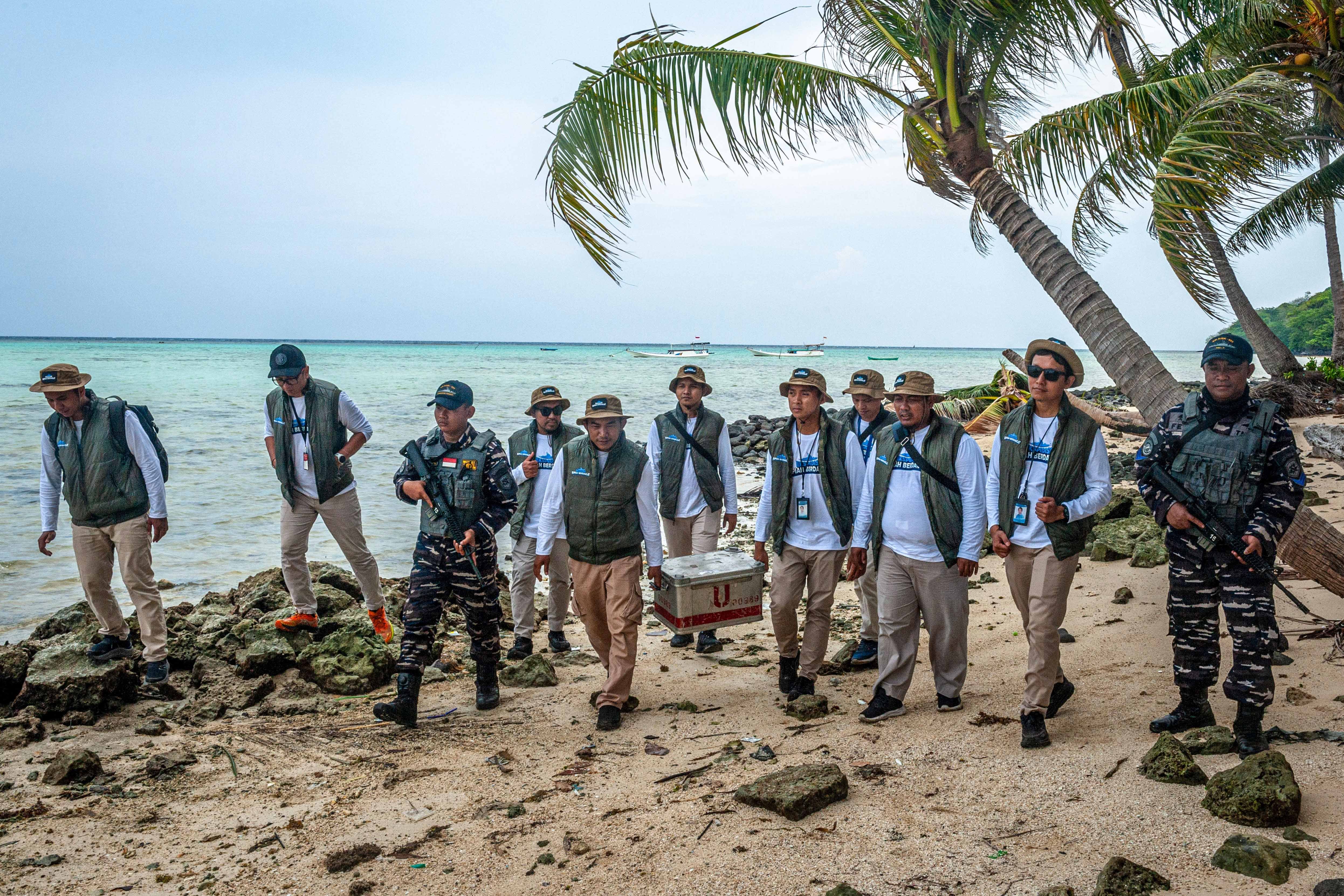 Dua personel KRI Ajak-653 mengawal tim ERK-2024 yang membawa kotak berisi uang rupiah di bibir pantai Pulau Genting, Kepulauan Karimunjawa, Jawa Tengah.