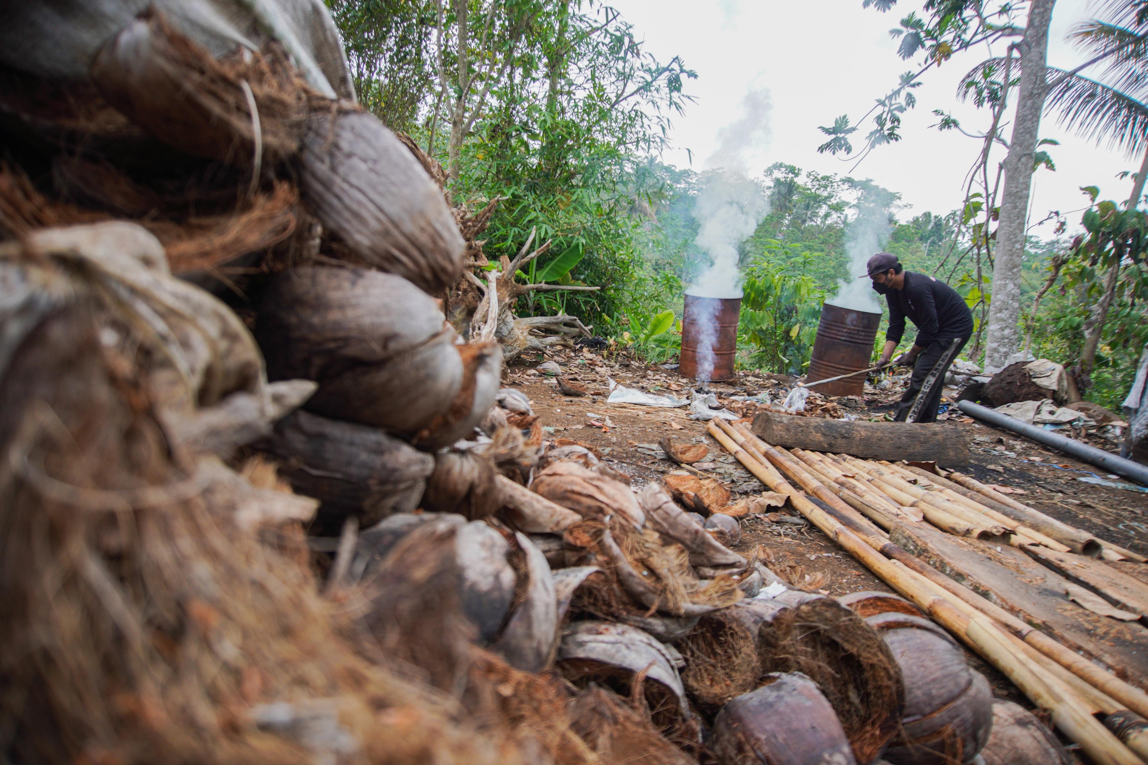 Pekerja mengumpulkan limbah batok kelapa untuk dibakar di Desa Gucialit, Lumajang, Jawa Timur.