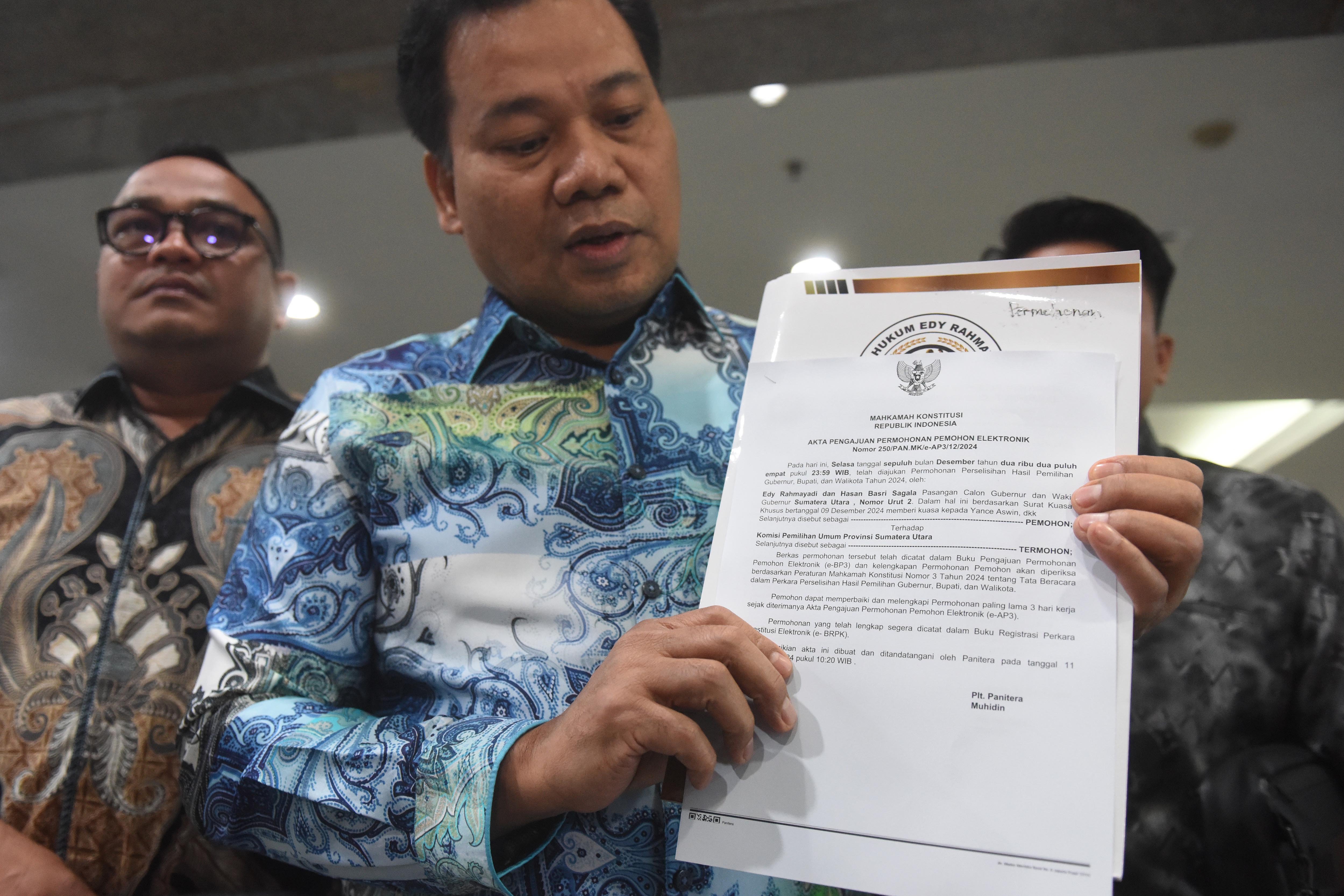Kuasa hukum dari pasangan cagub dan cawagub Sumut nomor urut 2 Edy Rahmayadi-Hasan Basri Sagala, Yance Aswin (kanan) menunjukkan berkas laporan pengajuan permohonan gugatan perselisihan hasil pilkada Sumatera Utara di Gedung Mahkamah Konstitusi, Jakarta,Rabu (11/12/2024). Pasangan Edy Rahmayadi-Hasan Basri Sagala resmi mengajukan gugatan sengketa pilkada Sumut ke Mahkamah Konstitusi usai kalah dalam perolehan suara dari pasangan cagub dan cawagub Sumut nomor urut 1 Bobby Nasution-Surya. 