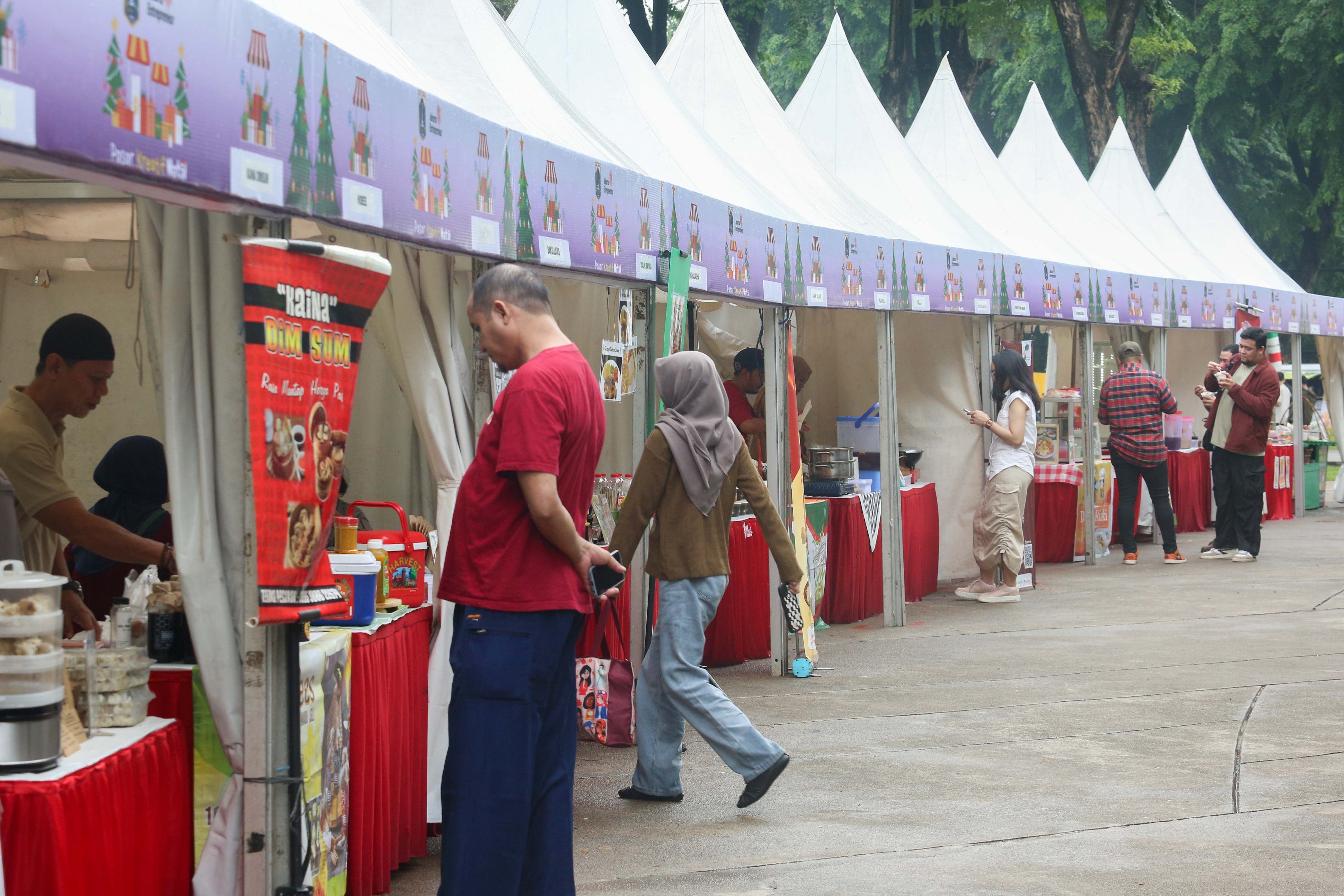 Pengunjung memesan makanan pada Pasar Kreatif Natal di Lapangan Banteng, Jakarta, Senin (23/12/2024). Kegiatan yang digelar dalam rangka menyambut Hari Raya Natal 2024 tersebut menghadirkan berbagai acara menarik mulai dari 70 stan UMKM makanan ringan dan produk kerajinan tangan, paduan suara kidung natal hingga penampilan musik dari Krisna Trias dan Moscato Band. 