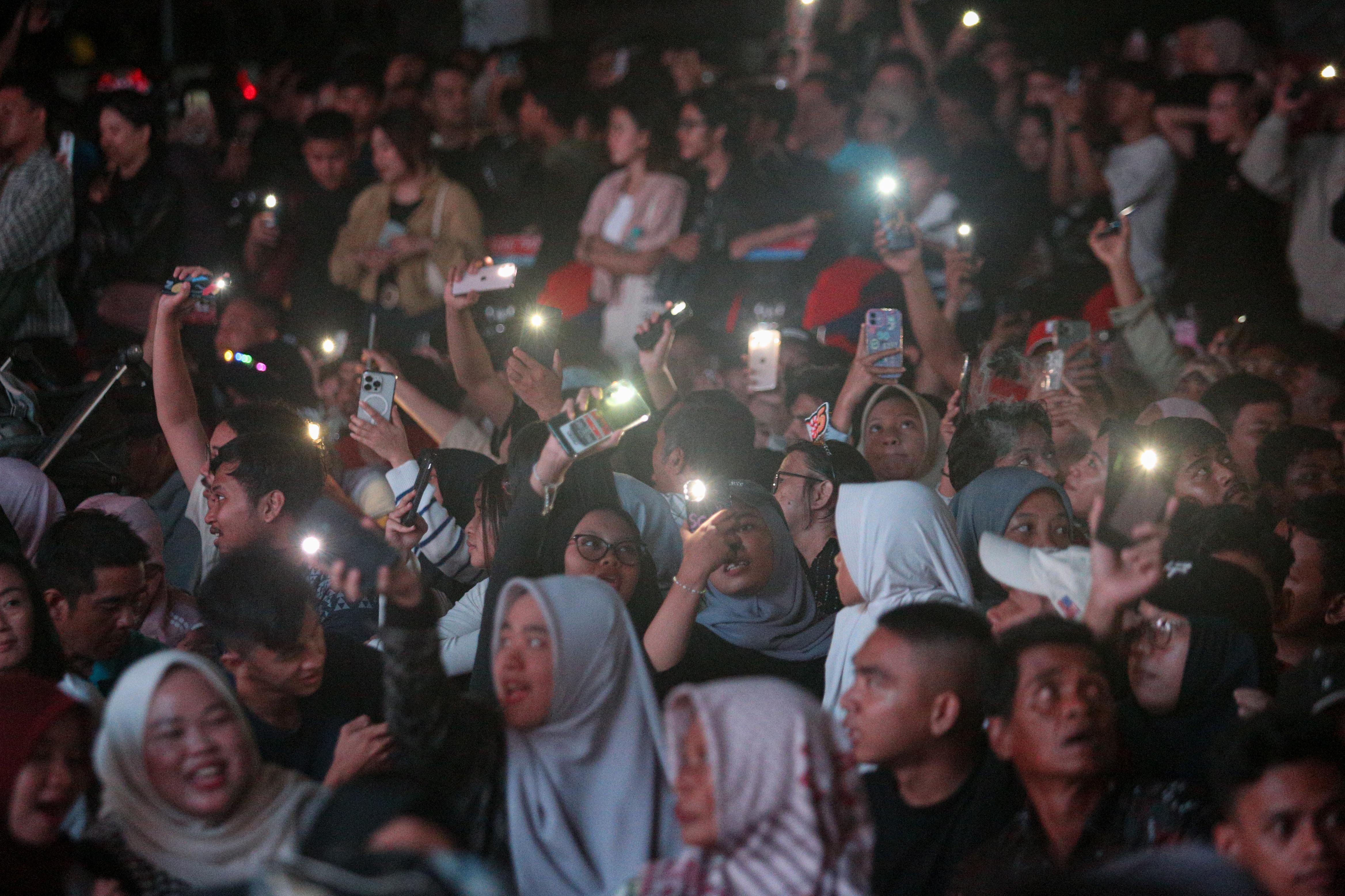 Sejumlah warga menyalakan lampu handphonenya saat menyaksikan penampilan Yura Yunita pada acara Kirana Jakarta 2025 di Bundaran HI, Jakarta, Selasa (31/12/2024). Pemprov Jakarta menggelar perayaan malam tahun baru 2025 dengan tema Semarak Jakarta Mendunia yang diisi oleh penampilan musik dari Yura Yunita dan RAN, pertunjukkan drone hingga pesta kembang api.