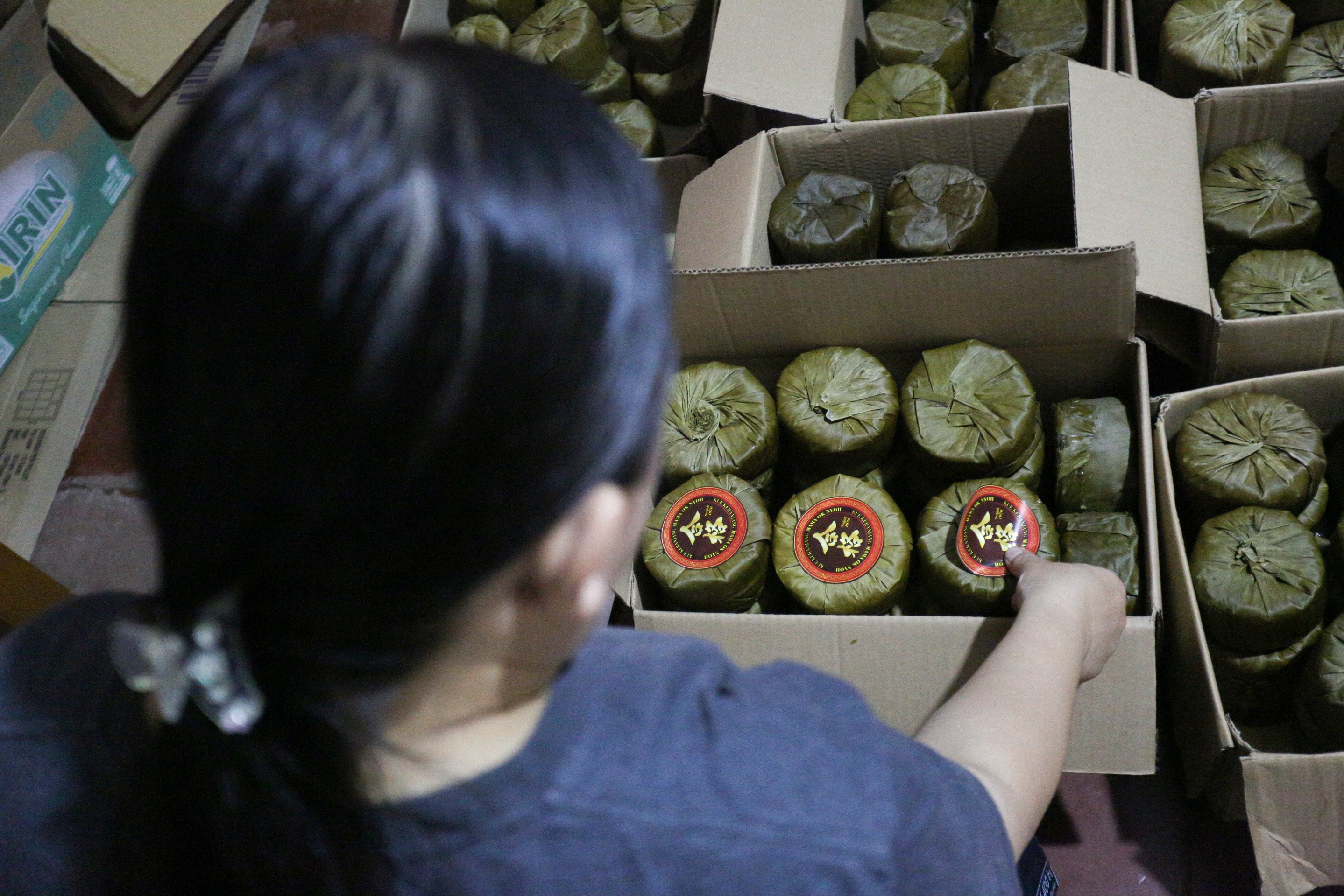 Riska (40) menempelkan stiker merek pada kue keranjang pesanan konsumen di rumah produksi Kue Keranjang Mama Ok Nyoh, Ciater, Kota Tangerang Selatan, Banten, Senin (20/1/2025). Menjelang Tahun Baru Imlek 2576 yang jauh pada 29 Januari 2025, produksi kue keranjang di tempat ini meningkat hingga dua kali lipat dengan total pesanan mencapai 500 kemasan per hari.