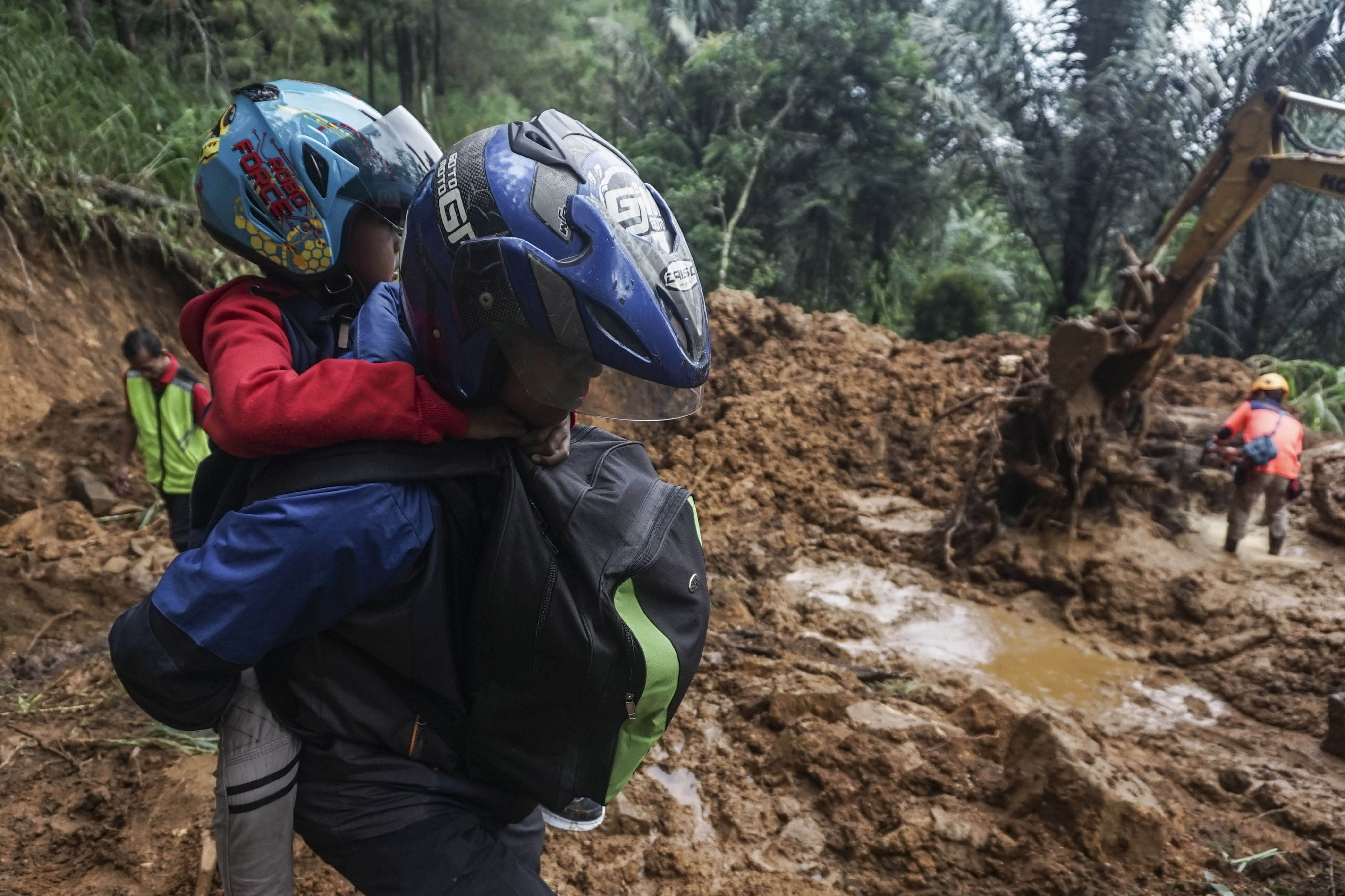 Warga menggendong keluarganya melewati material longsoran saat meninggalkan rumahnya pada hari kedua bencana longsor di Kecamatan Petungkriyono, Kabupaten Pekalongan, Jawa Tengah, Rabu (22/1/2025). Warga di sekitar bencana longsor memilih mengungsi untuk menghindari kemungkinan longsor susulan dikarenakan curah hujan masih cukup tinggi. 