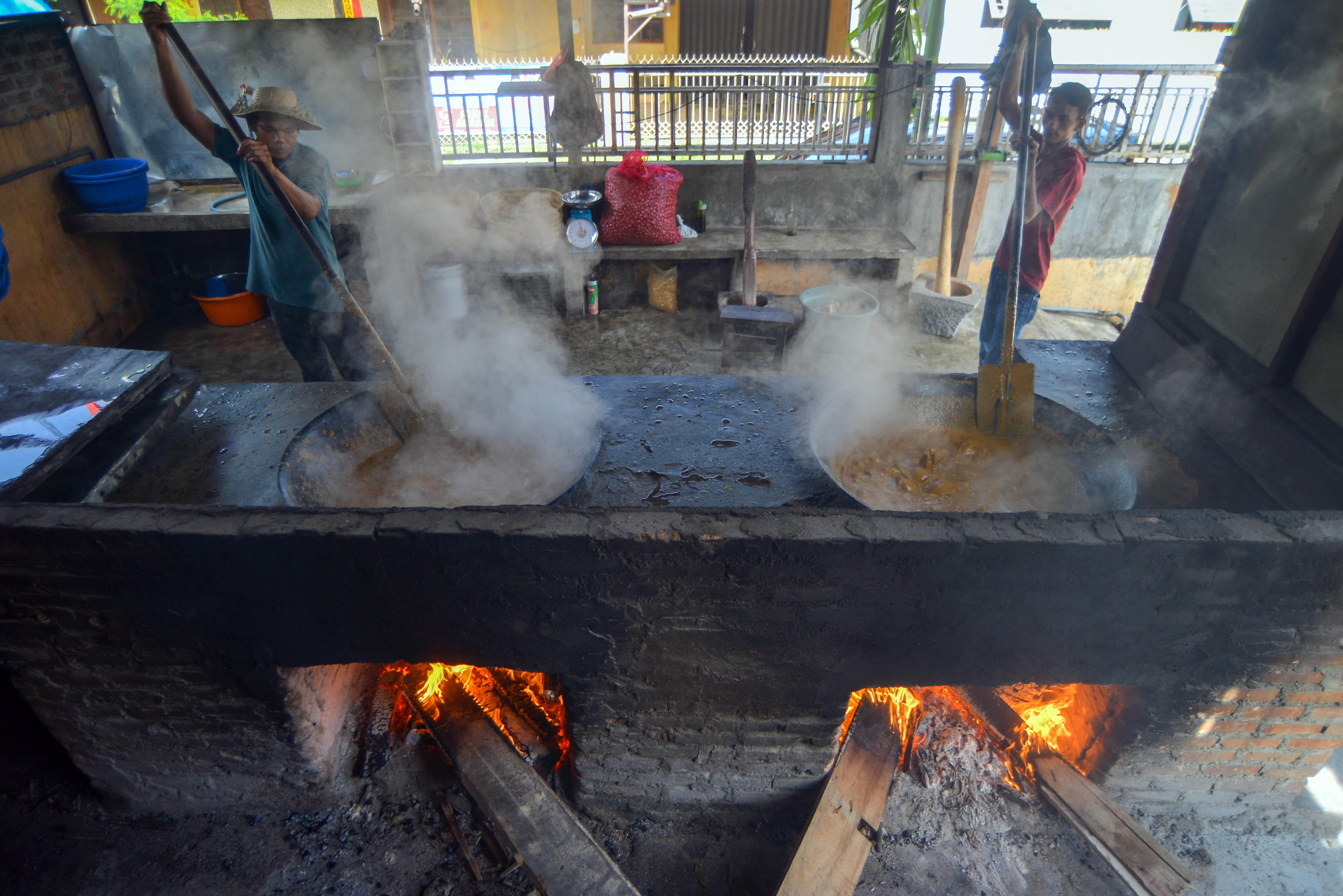 Juru masak mengaduk santan untuk randang yang dimasak dengan kayu bakar selama enam jam di warung makan Rajo-rajo, Padang.