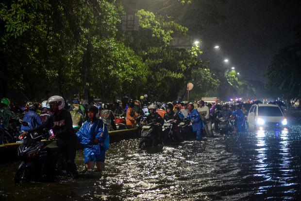 Sejumlah pengendara motor menuntun motornya melewati banjir di Jalan Daan Mogot, Cengkareng, Jakarta, Selasa (28/1/2025). Banjir setinggi 50 sentimeter akibat tingginya intensitas hujan tersebut membuat sejumlah kendaraan mogok dan lalu lintas jalan tersendat.