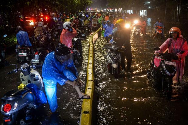 Sejumlah pengendara motor menuntun motornya melewati banjir di Jalan Daan Mogot, Cengkareng, Jakarta, Selasa (28/1/2025). Banjir setinggi 50 sentimeter akibat tingginya intensitas hujan tersebut membuat sejumlah kendaraan mogok dan lalu lintas jalan tersendat.