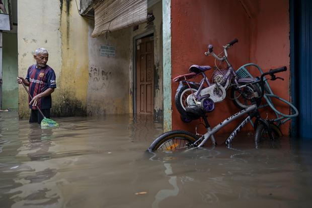 Seorang warga berdiri di depan rumahnya yang terendam banjir di Rawa Terate, Cakung, Jakarta Timur, Rabu (29/1/2025). BPBD DKI Jakarta mencatat sebanyak 54 RT dan 23 ruas jalan tergenang banjir yang terjadi akibat hujan lebat di wilayah Jakarta sejak Selasa (28/1) malam.