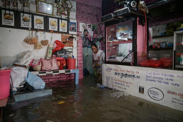 Seorang warga berdiri di dalam rumahnya yang terendam banjir di Rawa Terate, Cakung, Jakarta Timur, Rabu (29/1/2025). BPBD DKI Jakarta mencatat sebanyak 54 RT dan 23 ruas jalan tergenang banjir yang terjadi akibat hujan lebat di wilayah Jakarta sejak Selasa (28/1) malam.