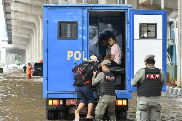 Petugas Satpol PP membantu pekerja untuk melintasi genangan air menggunakan truk di Jalan Boulevard Barat Raya, Kelapa Gading, Jakarta Utara, Rabu (29/1/2025). BPBD DKI Jakarta menuturkan 20 ruas Jalan di Jakarta tergenang air akibat intensitas hujan yang tinggi pada (28/1) dan kualitas saluran pembuangan air ke kali yang tidak lancar.