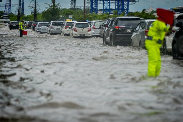 Polisi mengatur lalu lintas kendaraan saat banjir di Jalan Tol Sedyatmo, Cengkareng, Jakarta, Rabu (29/1/2025). Jalan tol yang merupakan akses menuju Bandara Soekarno-Hatta tersebut terendam banjir setinggi 20-30 sentimeter akibat tingginya intensitas hujan.