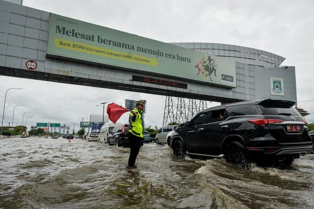 Polisi mengatur lalu lintas kendaraan saat banjir di Jalan Tol Sedyatmo, Cengkareng, Jakarta, Rabu (29/1/2025). Jalan tol yang merupakan akses menuju Bandara Soekarno-Hatta tersebut terendam banjir setinggi 20-30 sentimeter akibat tingginya intensitas hujan.