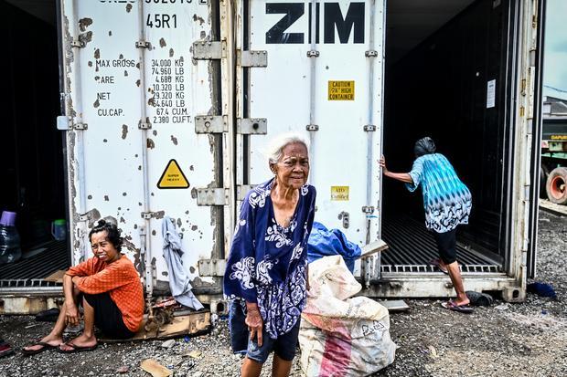 Sejumlah pengungsi beristirahat di depan kontainer kosong di Rorotan, Jakarta, Jumat (31/1/2025). Warga Kampung Sepatan, RT 18/05, Rorotan, Cilincing terpaksa mengungsi ke kontainer kosong setelah kediamannya terendam banjir setinggi satu meter.