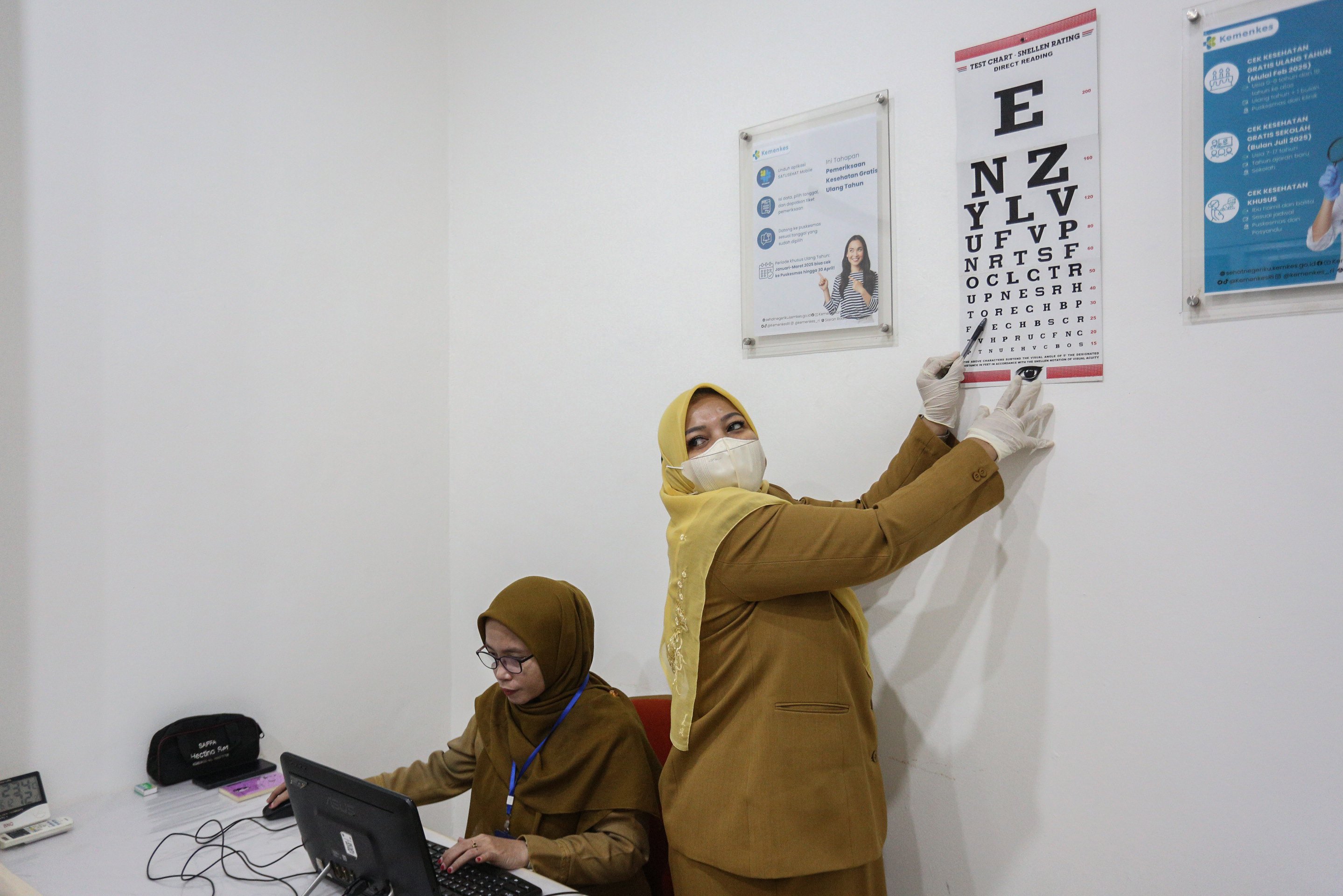 Petugas menunjuk huruf saat mengecek kesehatan mata pasien pada program pemeriksaan kesehatan gratis di Puskesmas Makasar, Jakarta Timur, Senin (10/2/2025). Pemerintah resmi memulai program Pemeriksaan Kesehatan Gratis bagi warga yang berulang tahun secara serentak di sekitar 10.200 puskesmas di seluruh Indonesia yang dilakukan dengan mengecek kondisi tubuh pasien sehingga deteksi dini terhadap risiko adanya masalah kesehatan dapat dilakukan.