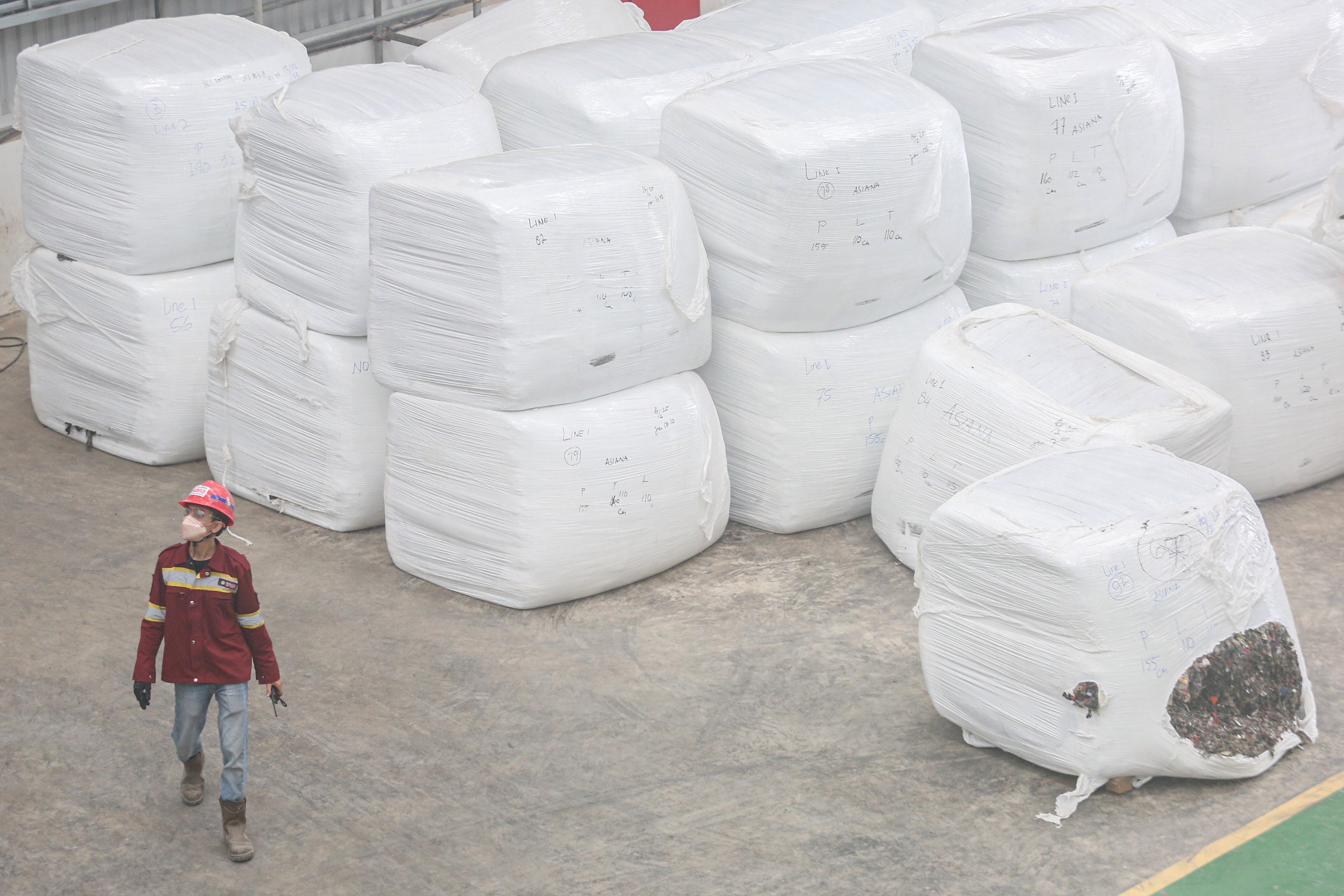 Pekerja berjalan di dekat sampah yang telah diolah di Refuse Derived Fuel (RDF) Plant Rorotan, Jakarta Utara, Selasa (25/2/2025). Pabrik pengolahan sampah yang mampu mengolah sebanyak 2.500 ton sampah per hari yang diubah menjadi bahan bakar alternatif ini menjadi solusi untuk mengurangi sekitar 30% volume sampah Jakarta yang dikirim ke Tempat Pengolahan Sampah Terpadu (TPST) Bantargebang.