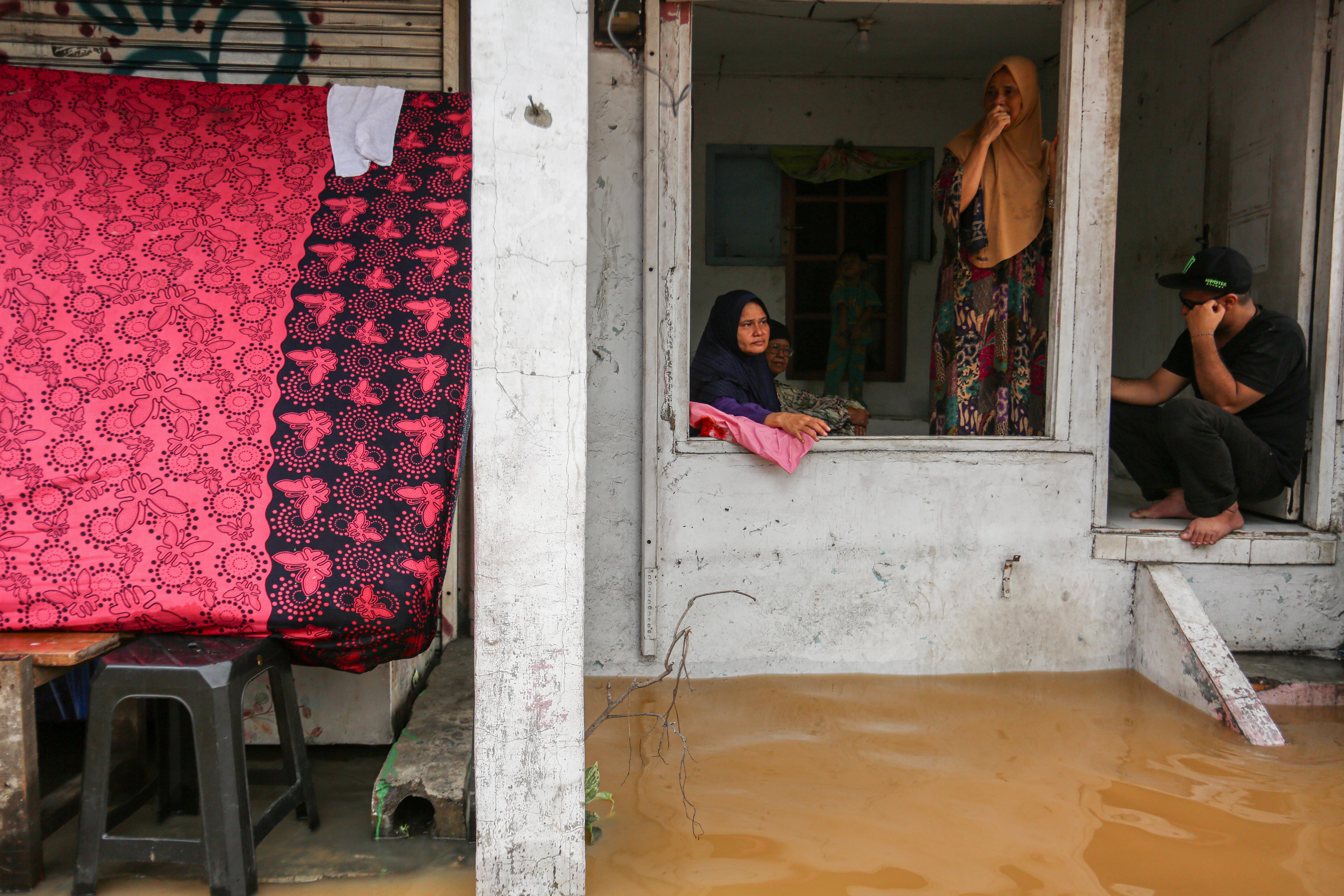 Sejumlah warga berada di depan rumahnya saat banjir merendam wilayah Cililitan, Kramat Jati, Jakarta Timur, Selasa (4/3/2025), Banjir yang merendam wilayah tersebut dengan ketinggian air mulai dari 30 cm hingga 300 cm itu disebabkan oleh meluapnya kali Ciliwung.