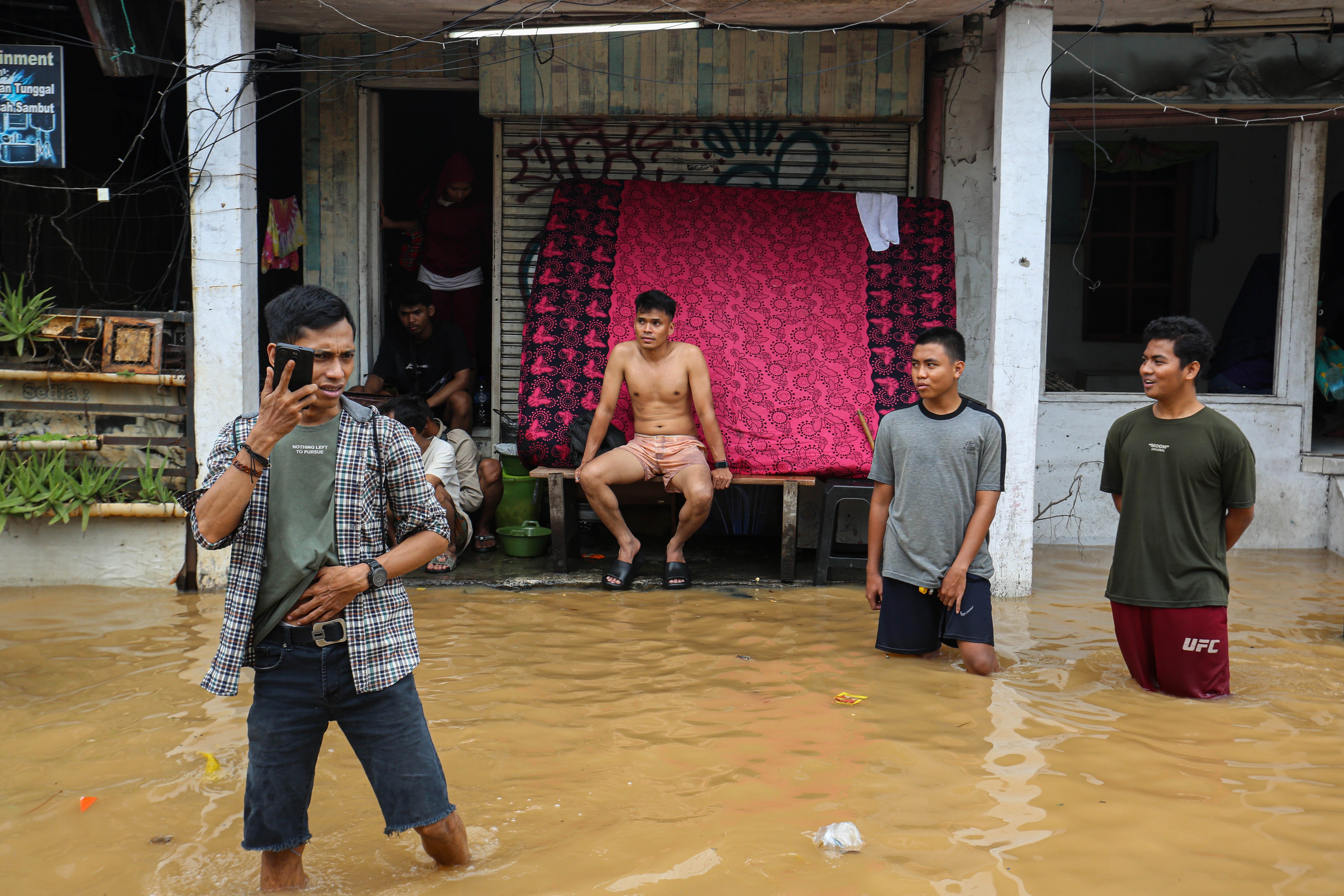 Sejumlah warga berada di depan rumahnya saat banjir merendam wilayah Cililitan, Kramat Jati, Jakarta Timur, Selasa (4/3/2025), Banjir yang merendam wilayah tersebut dengan ketinggian air mulai dari 30 cm hingga 300 cm itu disebabkan oleh meluapnya kali Ciliwung.
