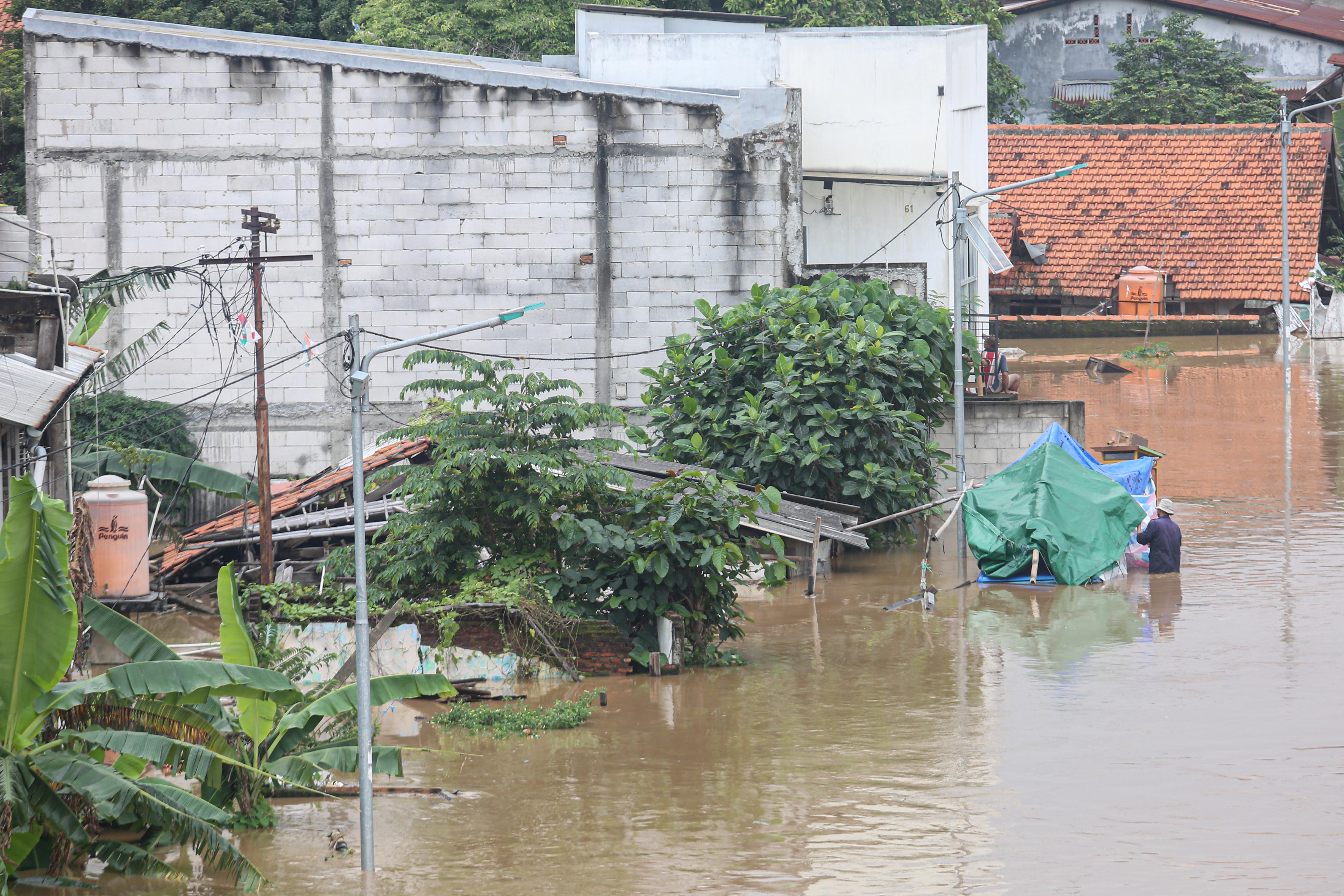 Warga melintasi banjir yang merendam wilayah Cililitan, Kramat Jati, Jakarta Timur, Selasa (4/3/2025), Banjir yang merendam wilayah tersebut dengan ketinggian air mulai dari 30 cm hingga 300 cm itu disebabkan oleh meluapnya kali Ciliwung.