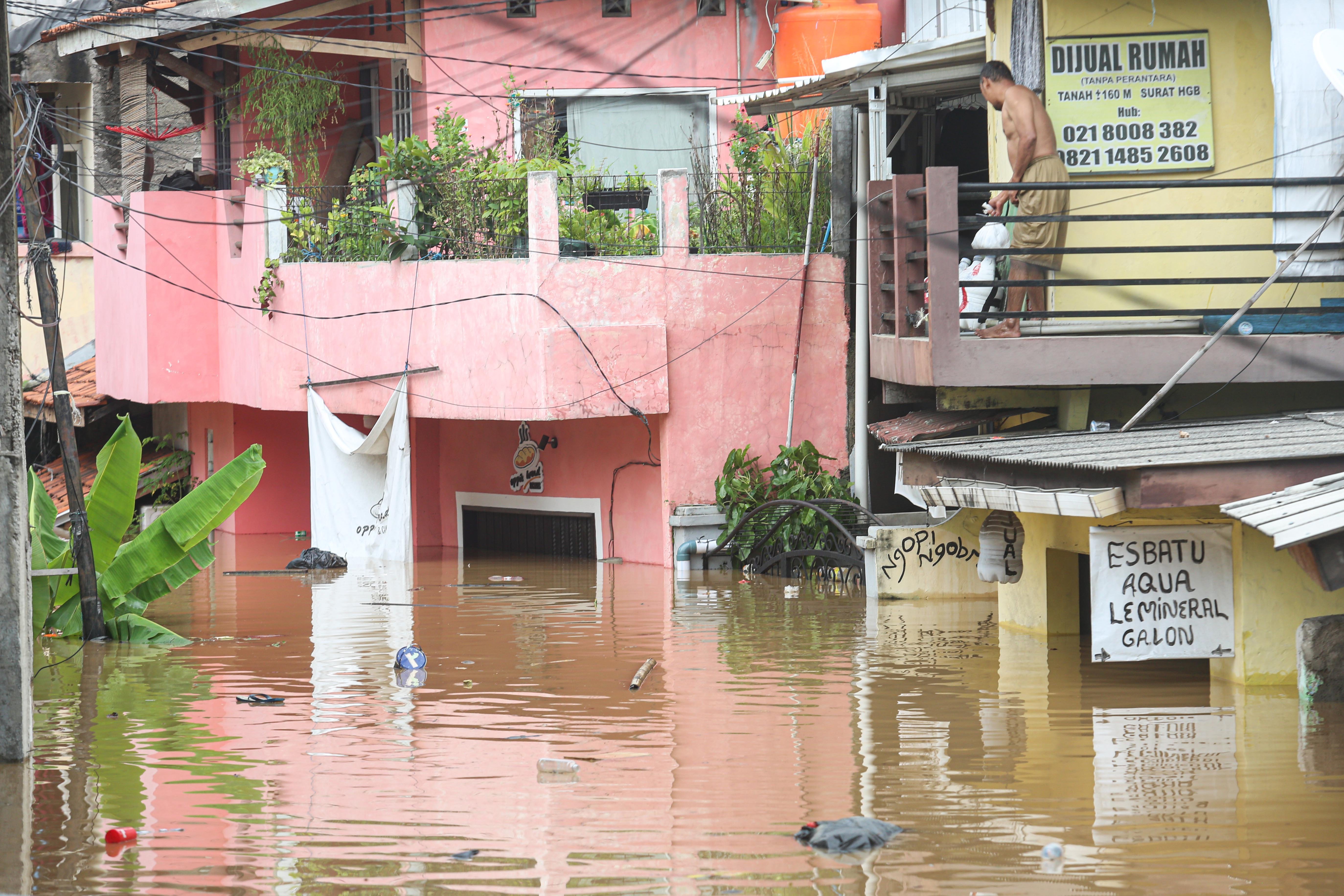 Warga berada di atas rumahnya saat banjir merendam wilayah Cililitan, Kramat Jati, Jakarta Timur, Selasa (4/3/2025), Banjir yang merendam wilayah tersebut dengan ketinggian air mulai dari 30 cm hingga 300 cm itu disebabkan oleh meluapnya kali Ciliwung.