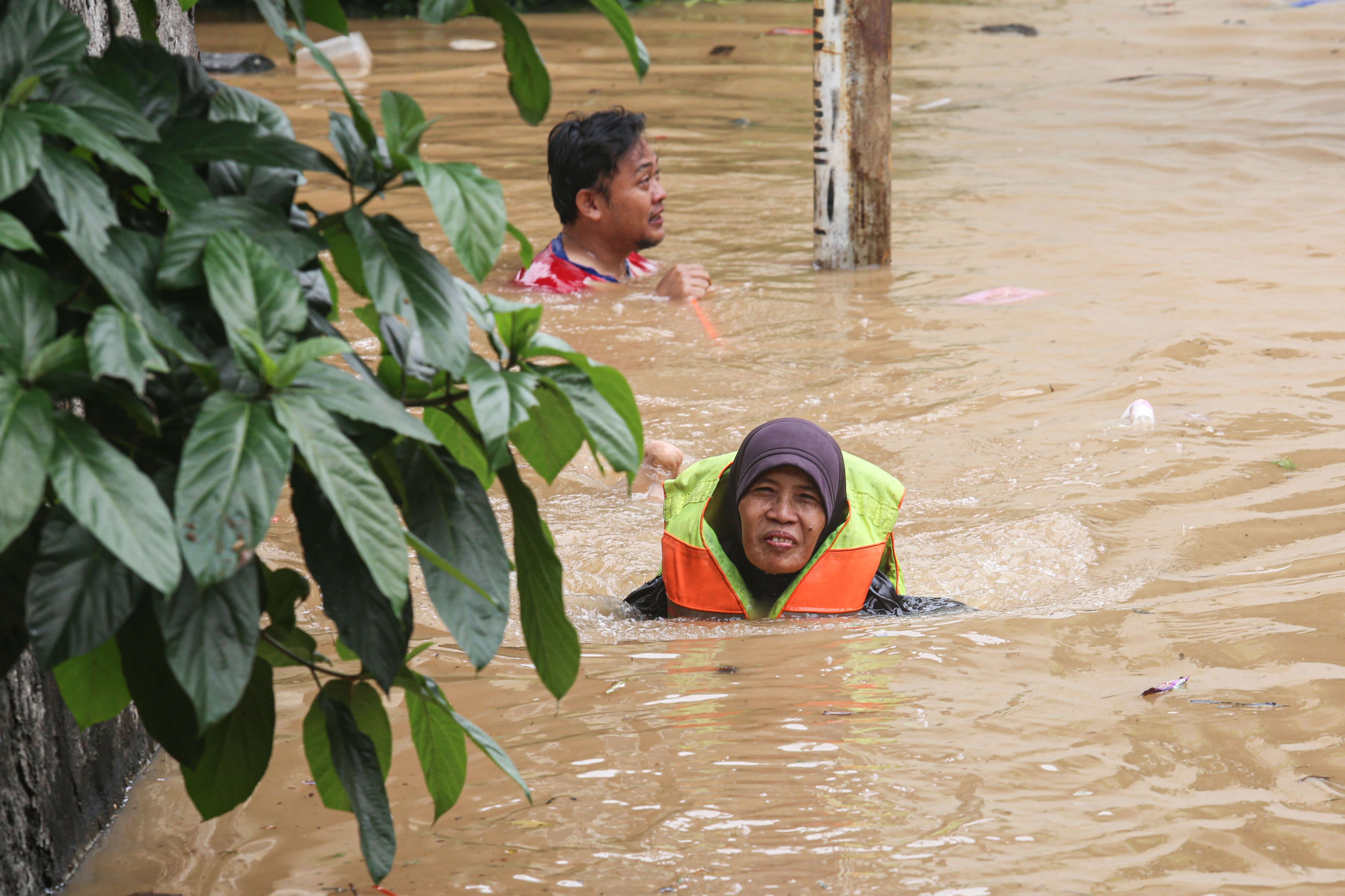 Warga menerobos banjir dengan mengenakan pelampung di wilayah Cililitan, Kramat Jati, Jakarta Timur, Selasa (4/3/2025), Banjir yang merendam wilayah tersebut dengan ketinggian air mulai dari 30 cm hingga 300 cm itu disebabkan oleh meluapnya kali Ciliwung.