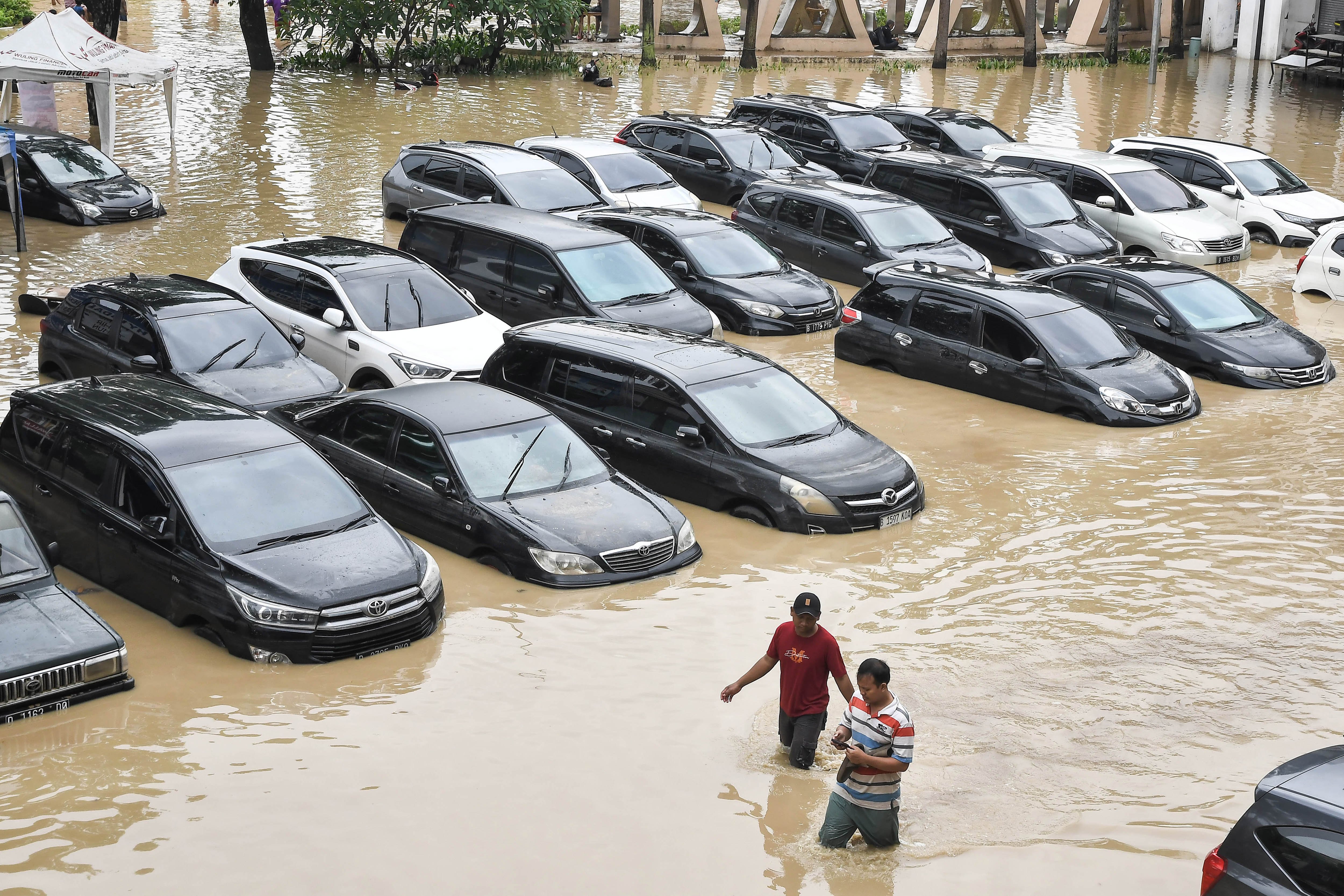Warga melintas disamping mobil yang terendam banjir di pertokoan Galaxy, Bekasi, Jawa Barat, Selasa (4/3/2025). Menurut data BPBD Kota Bekasi 20 titik banjir di Bekasi akibat luapan dari pertemuan Kali Cikeas dan Kali Cilengsi dengan ketinggian 20 - 300 cm. 