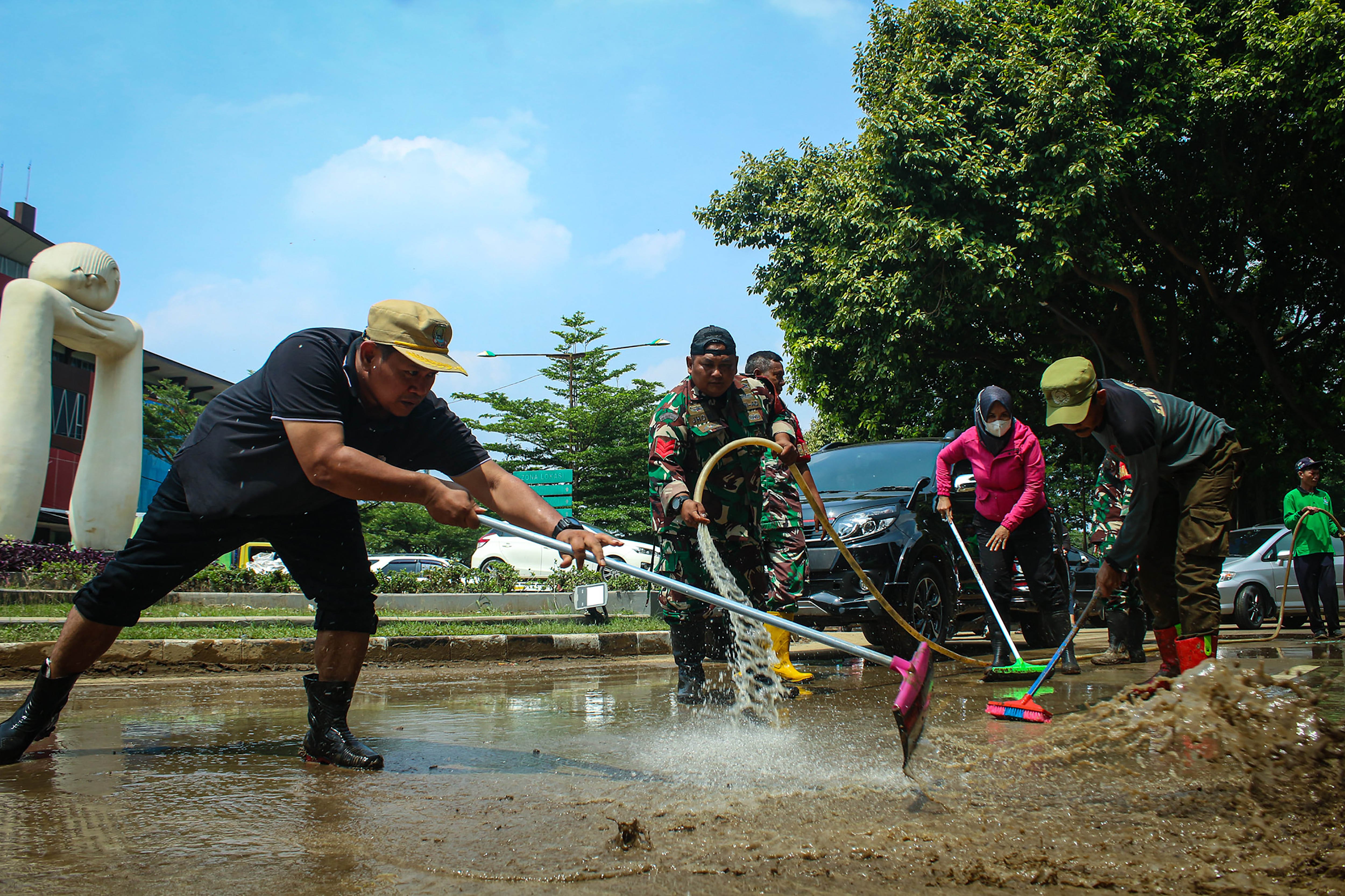 Petugas gabungan membersihkan lumpur di jalan pascabanjir yang melanda kawasan Kemang Pratama, Bekasi, Jawa Barat, Kamis (6/3/2025). Pembersihan lumpur dari sisa banjir tersebut dilakukan agar jalan itu dapat kembali dilintasi kendaraan. 