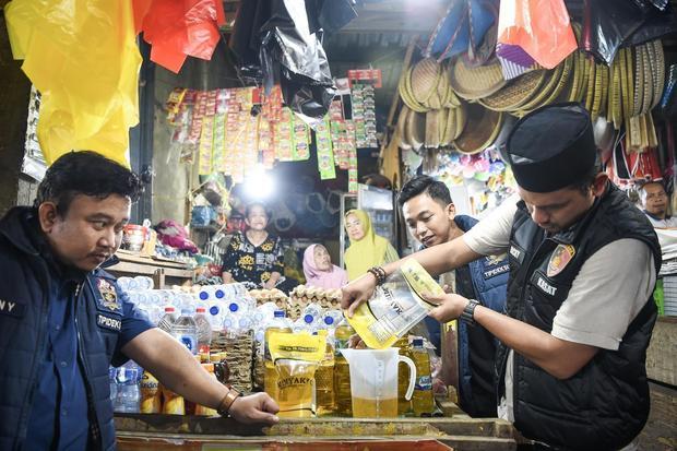 Kasatreskrim Polresta Samarinda AKP Dicky Anggi Pranata (kanan) didampingi satgas pangan menuangkan Minyakita kemasan pouch ke dalam gelas ukur saat melakukan sidak terhadap ketersediaan bahan pokok penting (bapokting) di Pasar Segiri, Samarinda, Kalimantan Timur, Selasa (11/3/2025). Satgas pangan Polresta Samarinda melakukan sidak ke gudang distributor dan pengecer sebagai tanggapan terhadap keresahan masyarakat terkait dugaan perbedaan isi minyak goreng dengan label yang tertera pada kemasan.