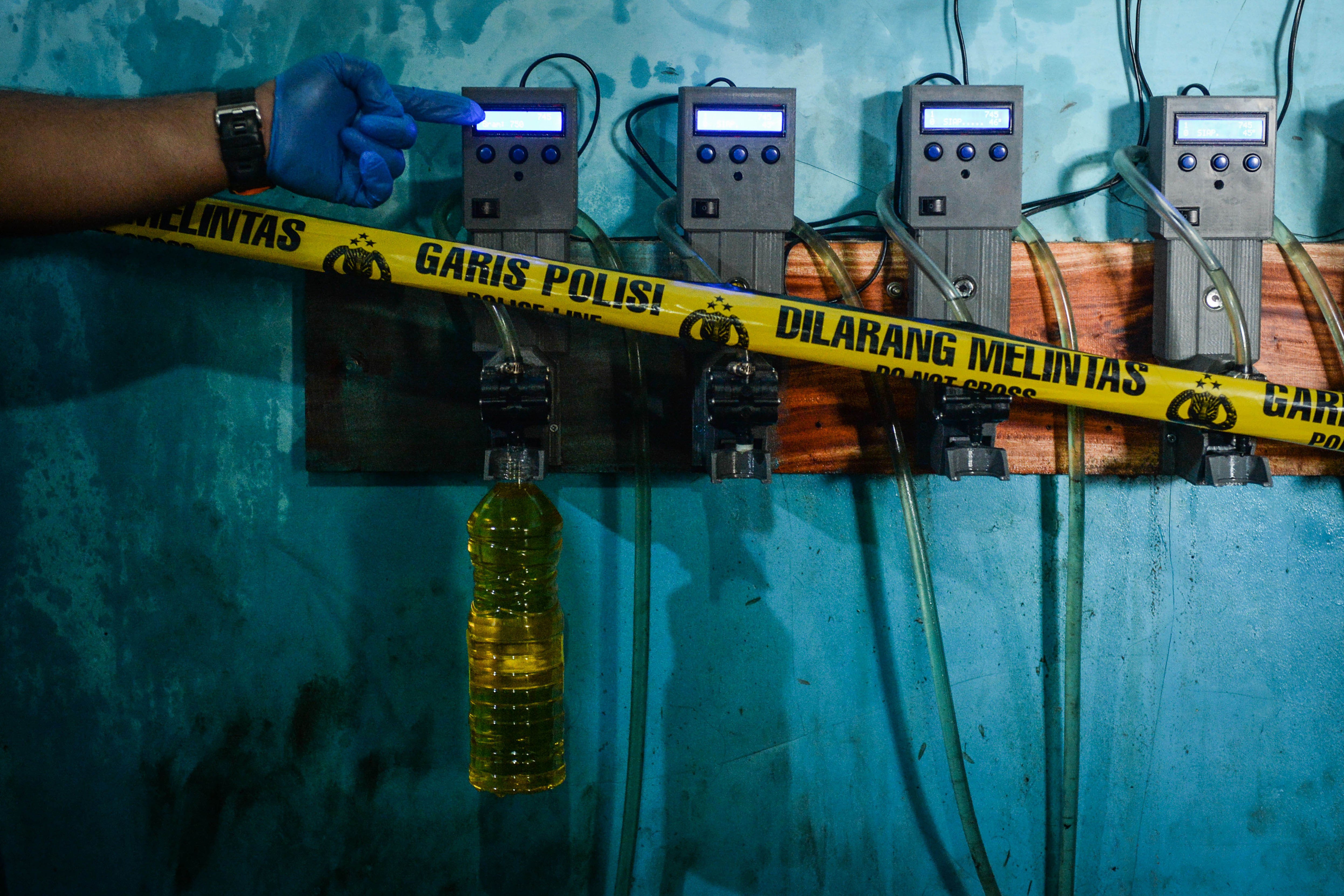 Polisi memperlihatkan proses pengisian MinyaKita tidak sesuai takaran saat rilis kasus di Desa Jambu Karya, Rajeg, Kabupaten Tangerang, Banten, Rabu (12/3/2025). Polda Banten mengungkap tempat produksi minyak goreng merek dagang MinyaKita dan Djernih yang melakukan pengurangan volume di setiap kemasan satu liter sebanyak 220-300 mililiter dengan barang bukti sebanyak 13 ton minyak curah dan seorang tersangka. 