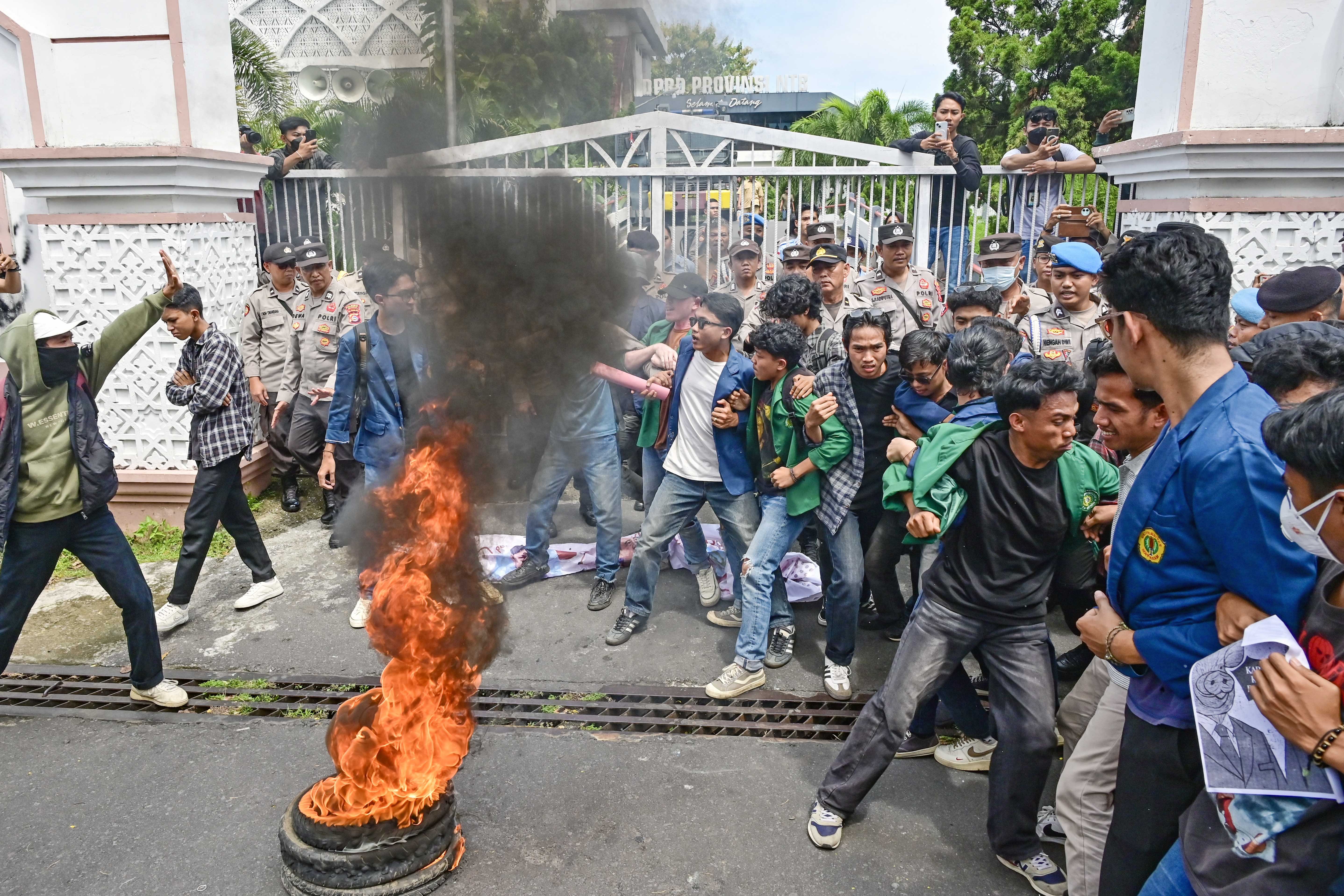 Pengunjuk rasa yang tergabung dalam Aliansi Mahasiswa dan Rakyat NTB membakar ban saat aksi menyikapi UU TNI di depan kantor DPRD NTB di Mataram, NTB, Selasa (25/3/2025). 
