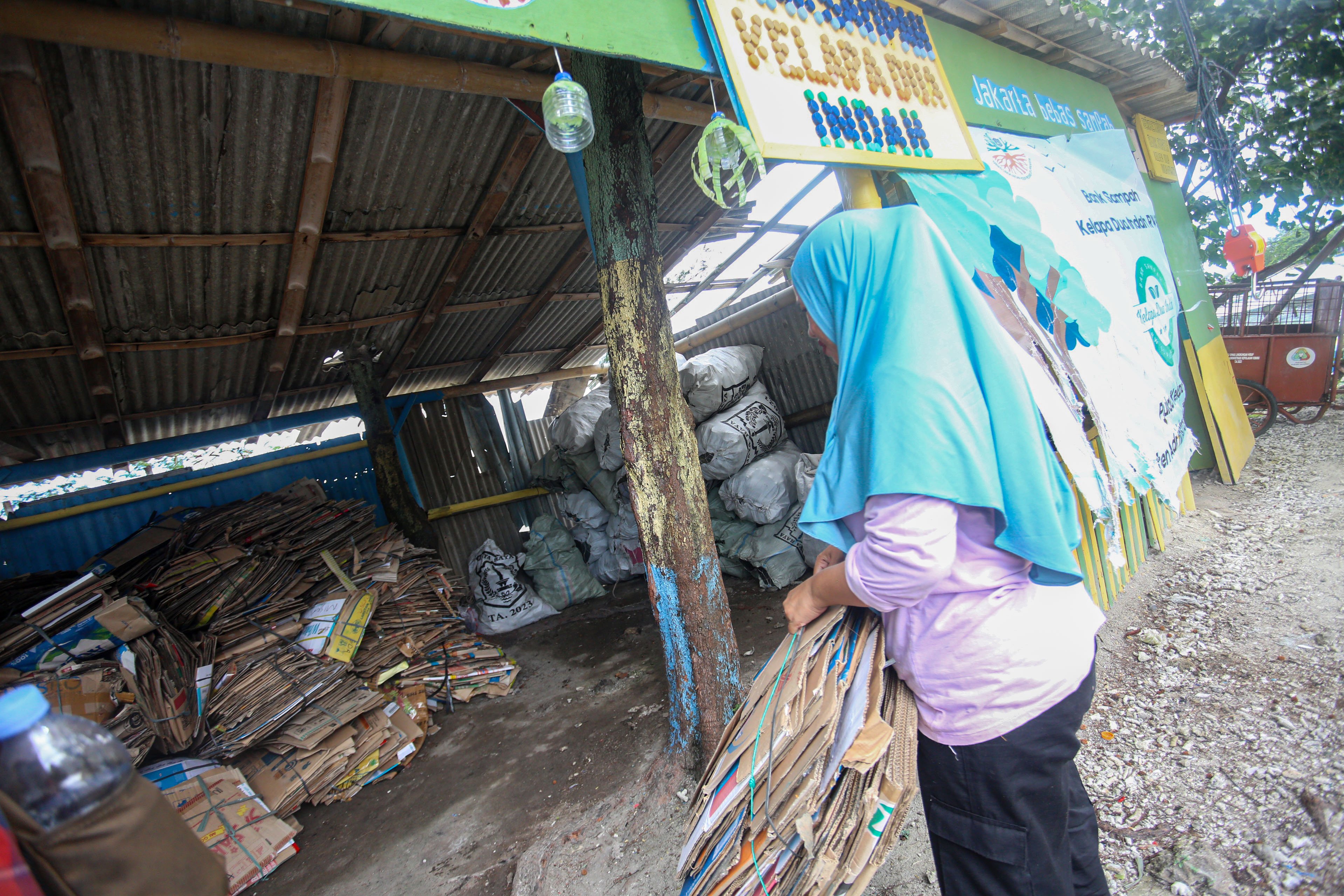 Anggota bank sampah membawa kardus bekas untuk disetorkan ke Bank Sampah Kelapa Dua Indah di Pulau Kelapa Dua, Kepulauan Seribu, Jakarta, Kamis (24/4/2025). Bank sampah yang telah beroperasi sejak tahun 2019 ini mampu berkontribusi dalam meningkatkan kesadaran dan partisipasi warga dalam pengelolaan sampah di pulau tersebut dan juga menjadi sumber pemasukan tambahan bagi warga melalui sampah yang disetorkan ke bank sampah.