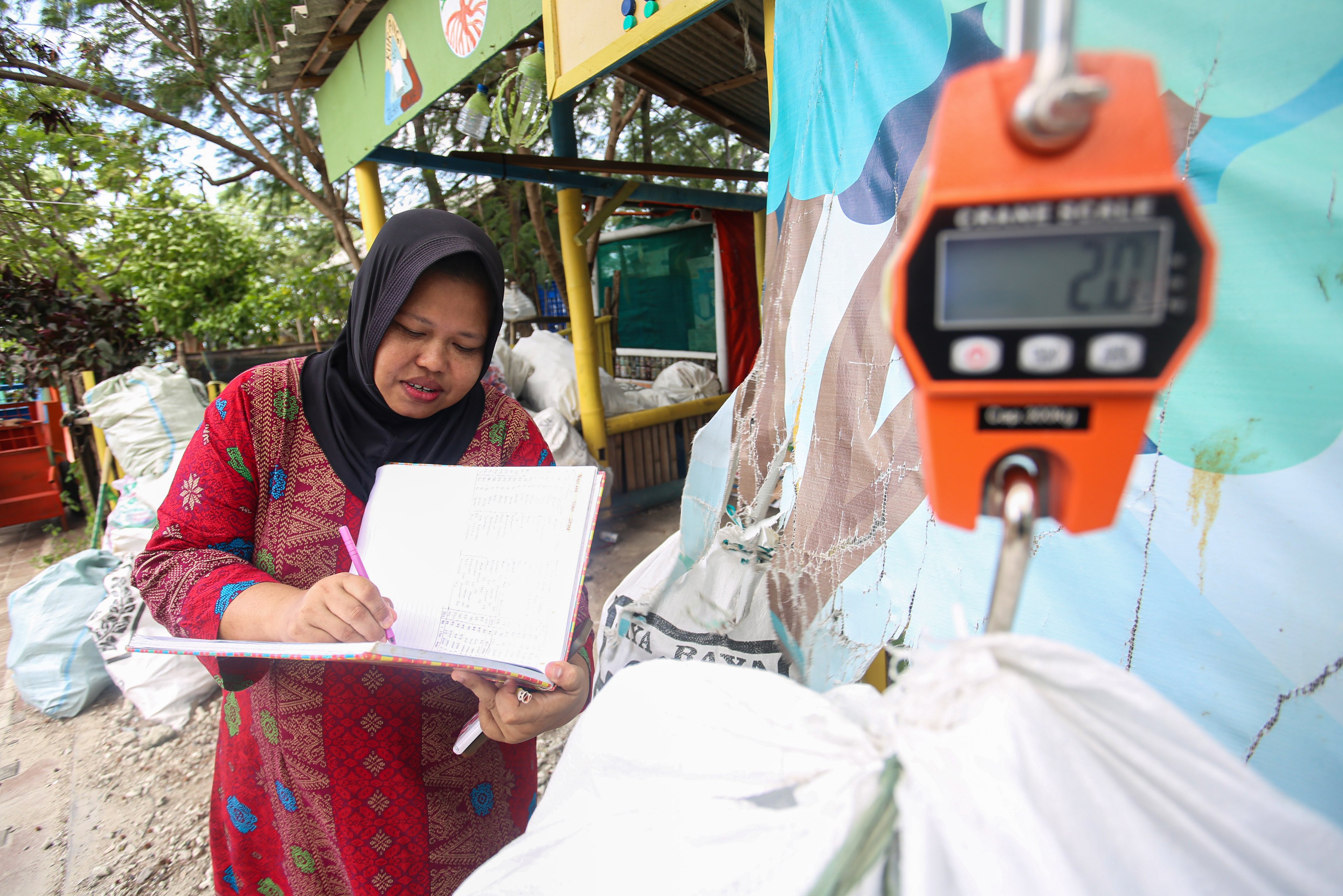 Ketua Bank Sampah Kelapa Dua Indah, Nuryanah mencatat hasil timbangan karung sampah plastik yang dibawa oleh anggota bank sampah di Pulau Kelapa Dua, Kepulauan Seribu, Jakarta, Kamis (24/4/2025). Bank sampah yang telah beroperasi sejak tahun 2019 ini mampu berkontribusi dalam meningkatkan kesadaran dan partisipasi warga dalam pengelolaan sampah di pulau tersebut dan juga menjadi sumber pemasukan tambahan bagi warga melalui sampah yang disetorkan ke bank sampah. 