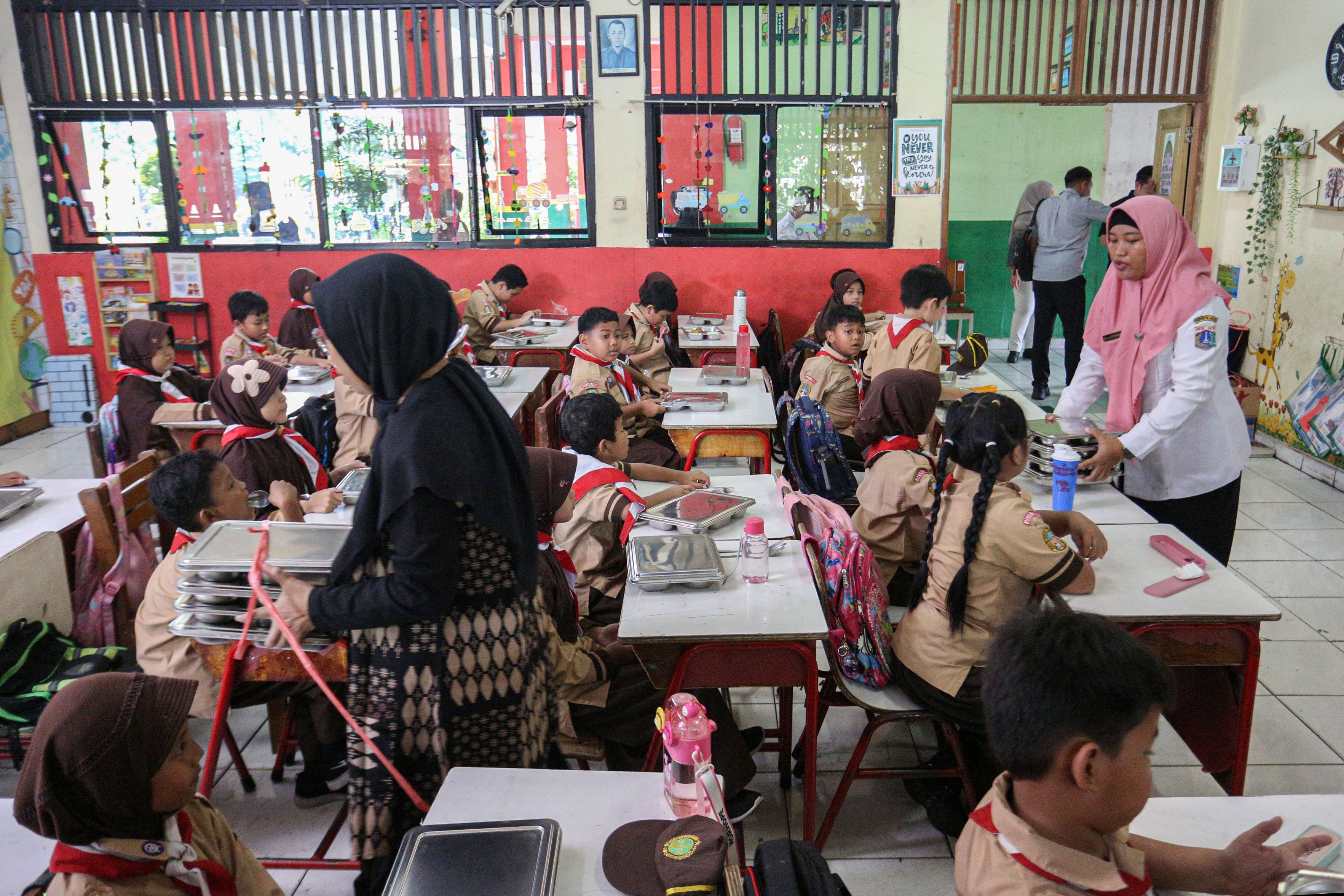 Guru membagikan makanan bergizi gratis saat Presiden Prabowo Subianto bersama pendiri Microsoft Bill Gates meninjau program Makan Bergizi Gratis (MBG) di SDN Jati 03, Pulogadung, Jakarta Timur, Rabu (7/5/2025). Pada kesempatan itu Presiden Prabowo Subianto dan Bill Gates turut meninjau pemeriksaan kesehatan gratis di sekolah tersebut. 