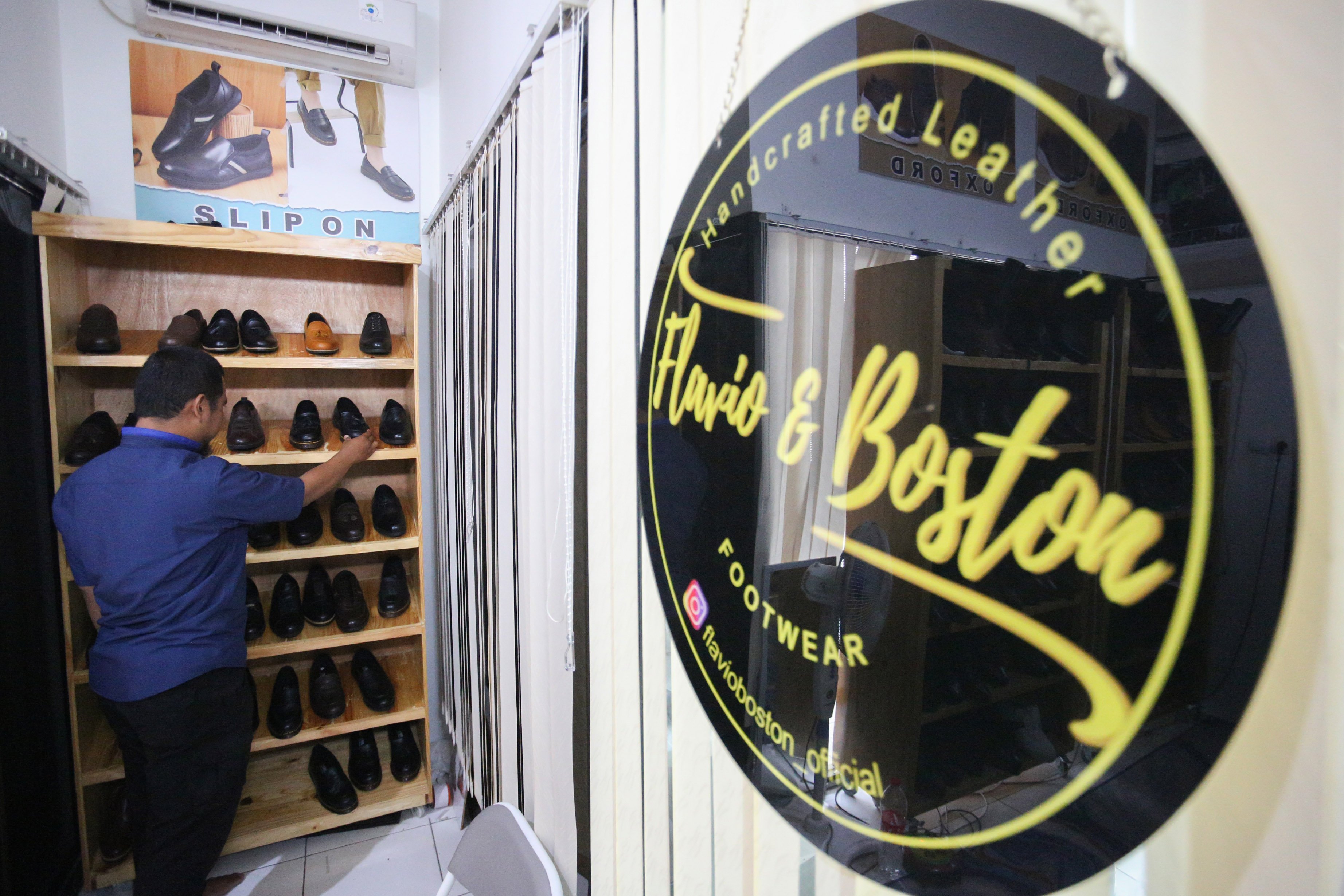 Rully (39) menata sepatu kulit yang dijual di rumah produksi sepatu kulit Flavio & Boston, Penggilingan, Cakung, Jakarta Timur, Kamis (8/5/2025). Industri rumahan yang telah beroperasi sejak tahun 1980 ini mampu menghasilkan 1000 pasang sepatu per bulannya dengan rata-rata penjualan sebanyak 800 hingga 900 pasang sepatu. 
