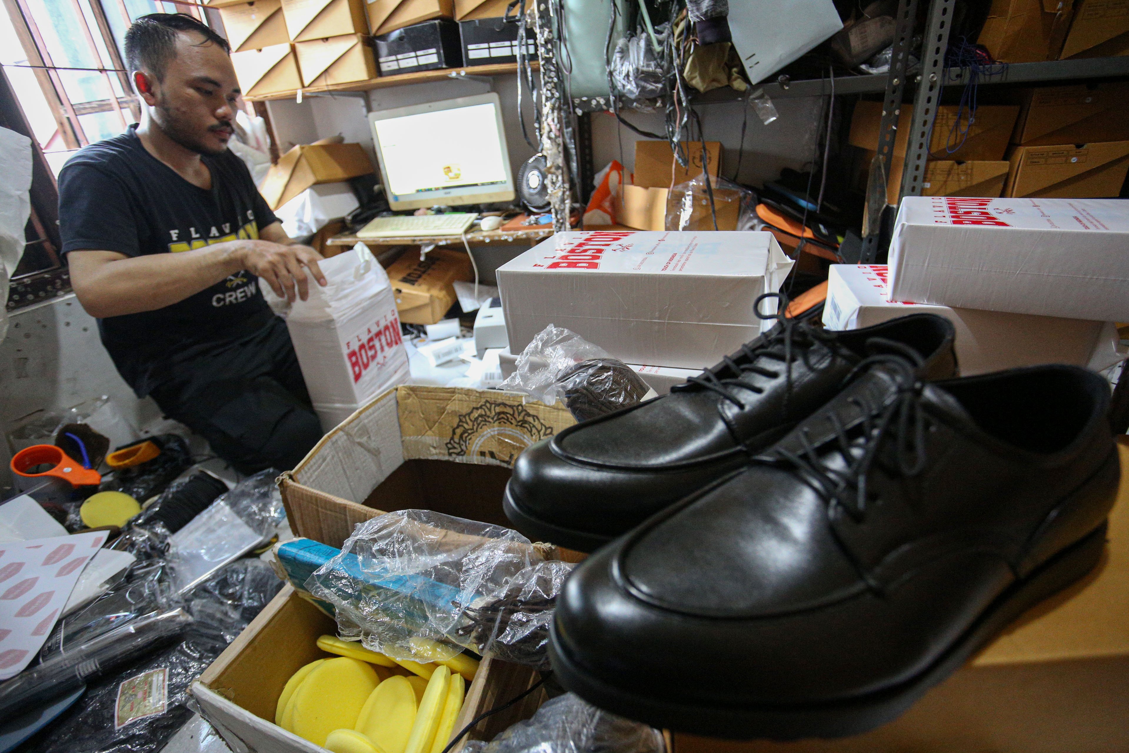 Pekerja mengemas sepatu pesanan pelanggan di rumah produksi sepatu kulit Flavio & Boston, Penggilingan, Cakung, Jakarta Timur, Kamis (8/5/2025). Industri rumahan yang telah beroperasi sejak tahun 1980 ini mampu menghasilkan 1000 pasang sepatu per bulannya dengan rata-rata penjualan sebanyak 800 hingga 900 pasang sepatu. 