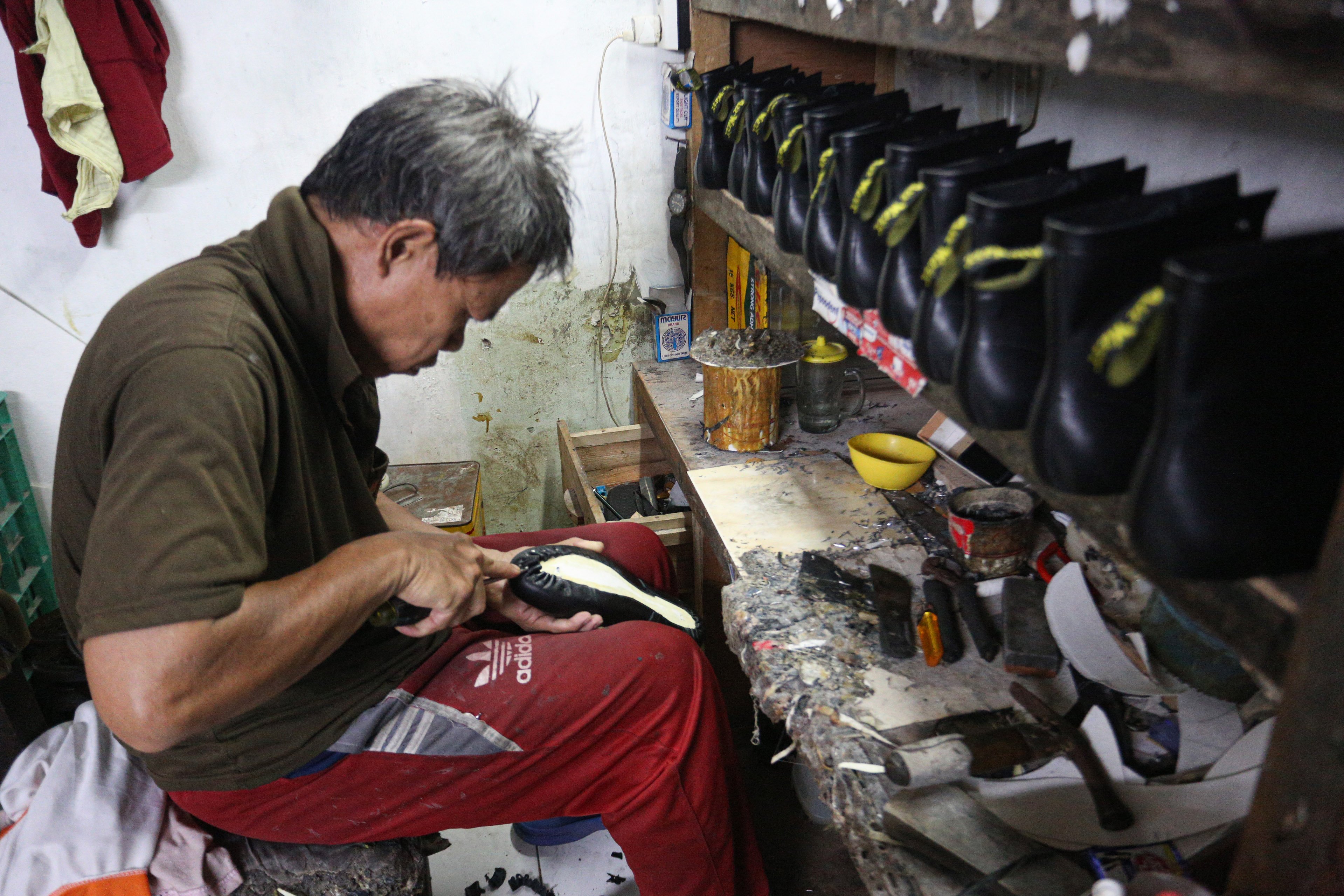 Pekerja menyelesaikan pembuatan sepatu di rumah produksi sepatu kulit Flavio & Boston, Penggilingan, Cakung, Jakarta Timur, Kamis (8/5/2025). Industri rumahan yang telah beroperasi sejak tahun 1980 ini mampu menghasilkan 1000 pasang sepatu per bulannya dengan rata-rata penjualan sebanyak 800 hingga 900 pasang sepatu.