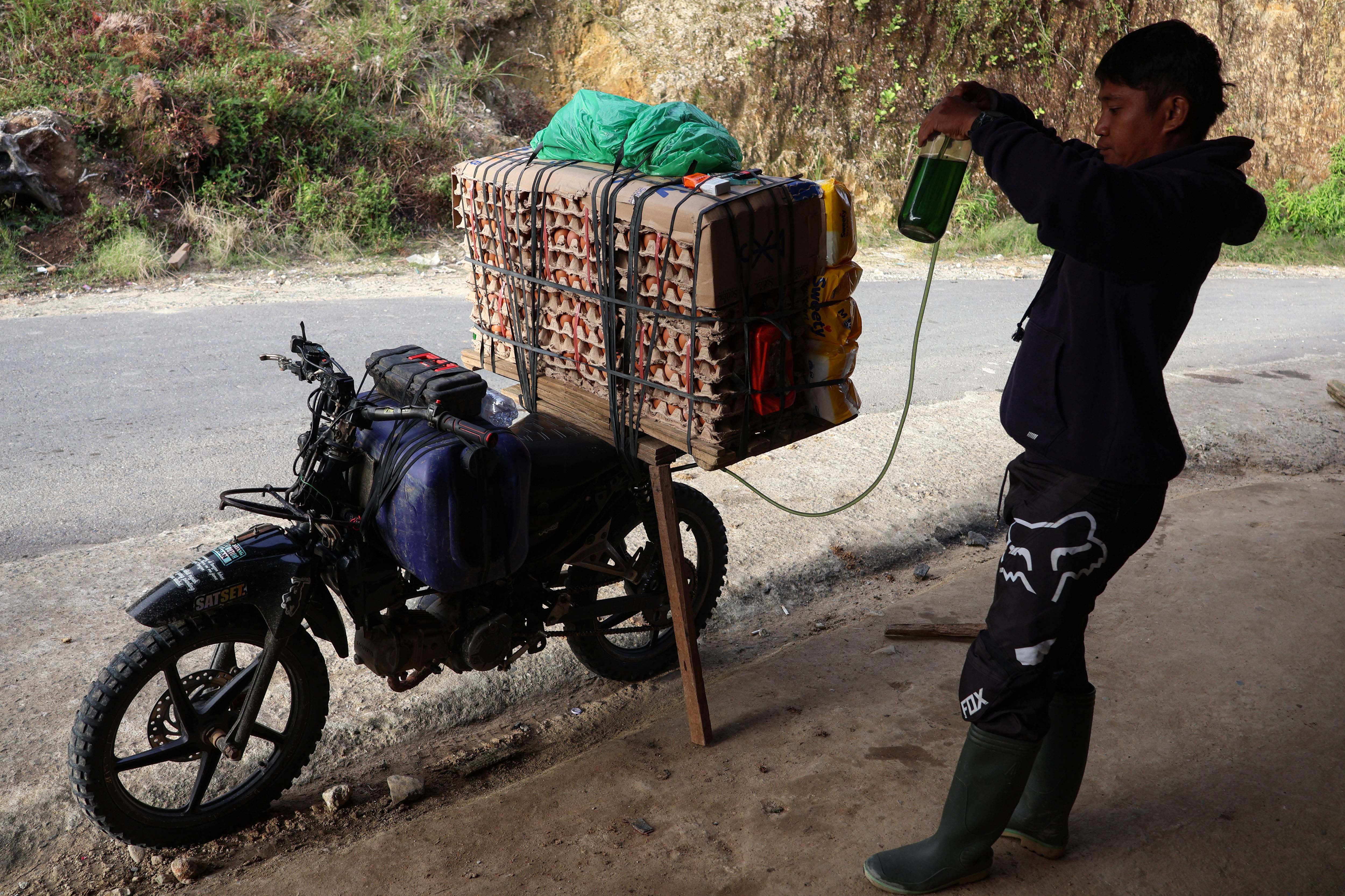 Tukang ojek mengisi BBM ke tangki motornya sebelum melanjutkan perjalanan menuju Kecamatan Seko di salah satu warung makan di Kecamatan Rongkong, Kabupaten Luwu Utara, Sulawesi Selatan. 