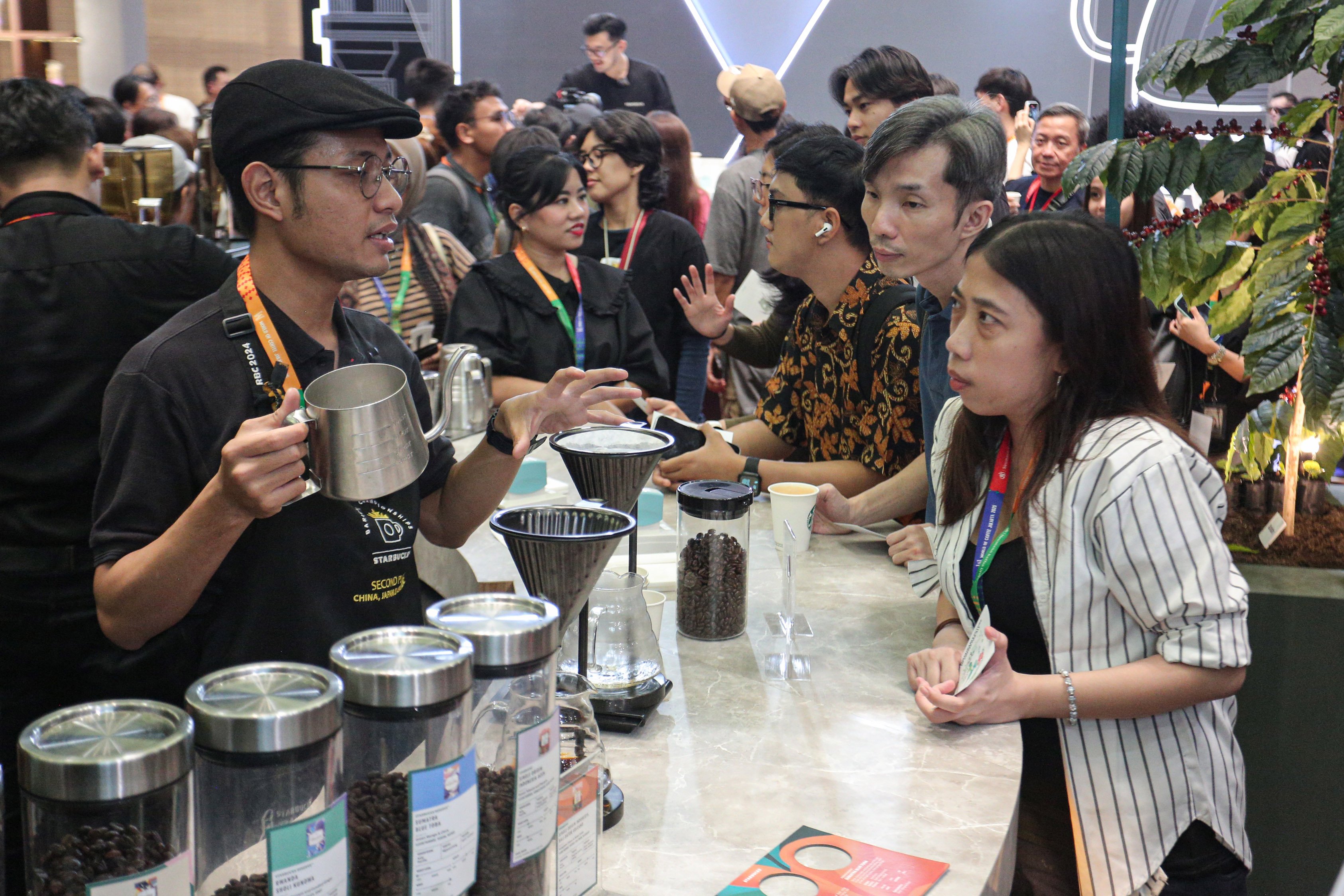Barista menjelaskan kopi yang disajikan kepada pengunjung pada pameran World of Coffee Jakarta 2025 di Jakarta International Convention Center (JICC), Kamis (15/5/2025). Pameran yang pertama kali diadakan di Indonesia dan berlangsung hingga 17 Mei 2025 ini diikuti oleh lebih dari 400 merek kopi terkemuka yang menjadi wadah bagi pelaku industri, pemerintah dan para profesional kopi global dalam menemukan peluang bisnis di industri tersebut. 
