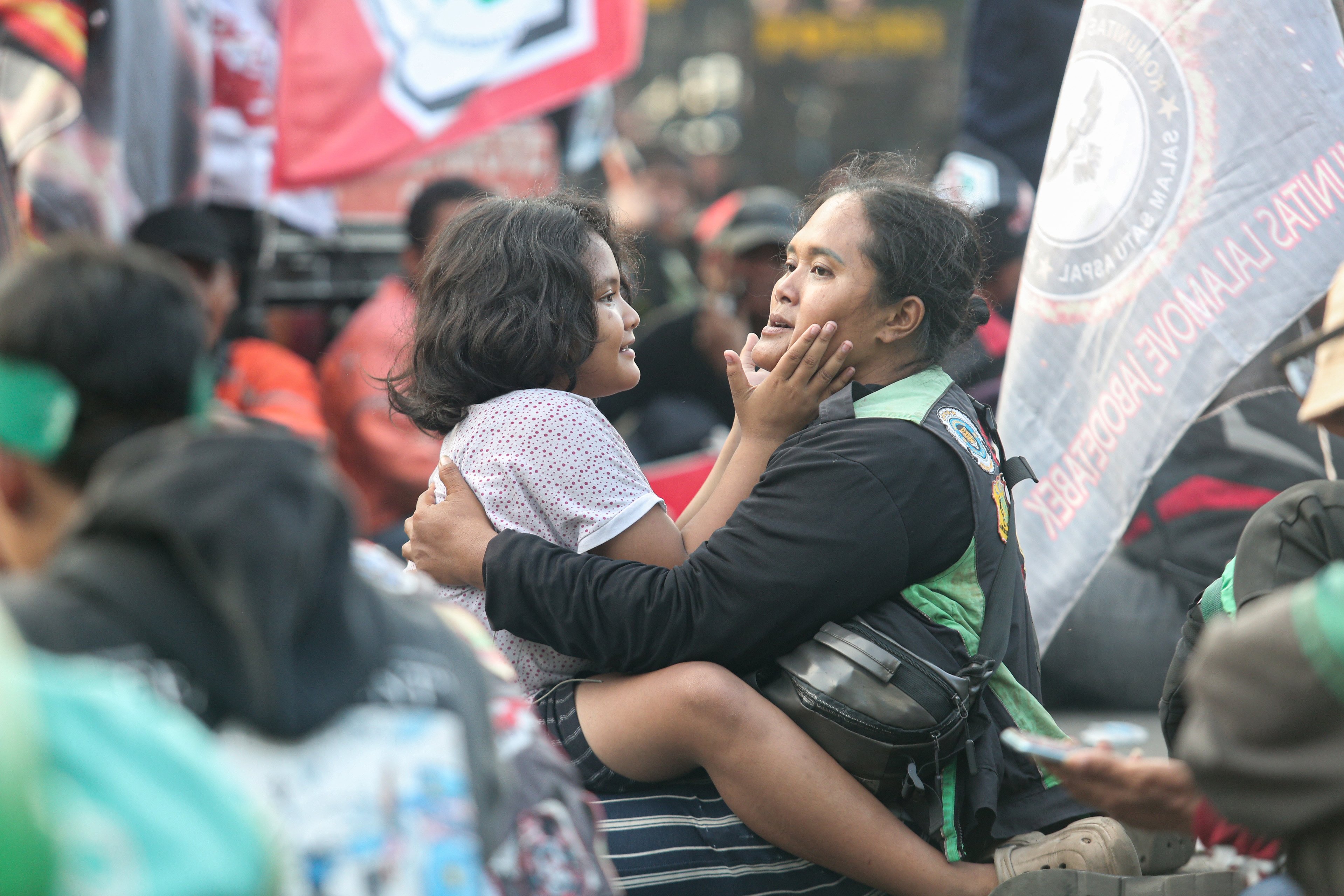 Seorang pengemudi ojek online (ojol) bersama anaknya saat mengikuti aksi demonstrasi di kawasan Patung Kuda, Monas, Jakarta Pusat, Selasa (20/5/2025). Dalam aksi ini mereka mendesak pemerintah agar memberikan sanksi tegas kepada perusahaan aplikasi yang melanggar peraturan batas maksimal potongan aplikator sebesar 20% dan menuntut agar potongan tersebut diturunkan menjadi 10% karena ketentuan sebelumnya dinilai memberatkan bagi pengemudi ojol.