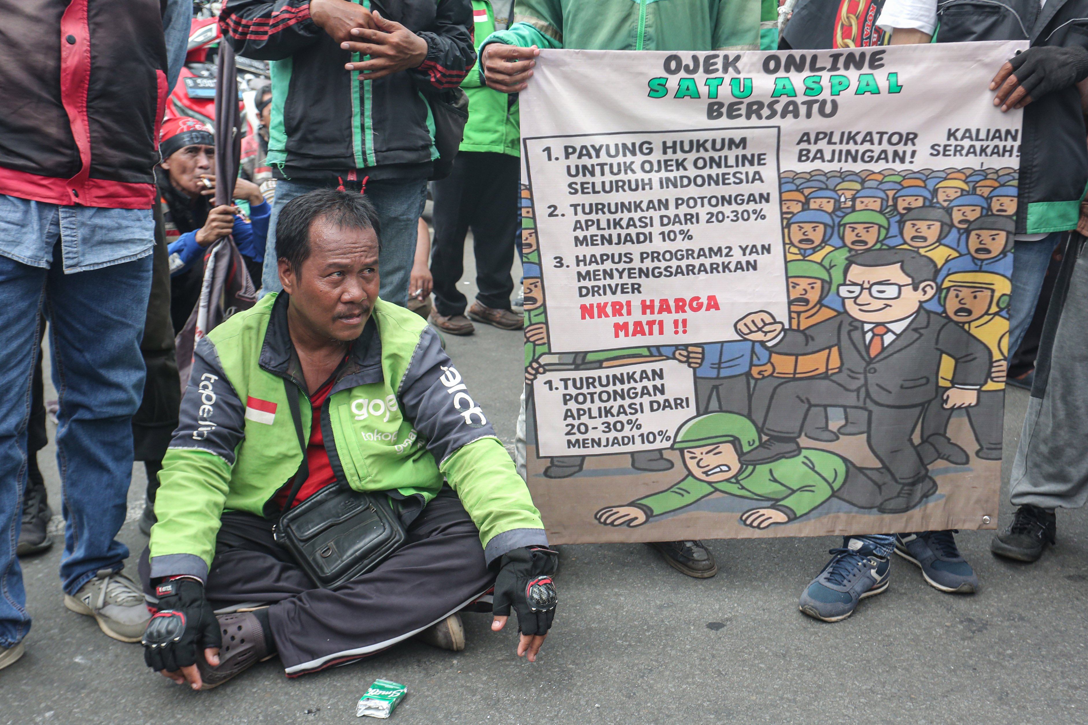 Sejumlah pengemudi ojek online (ojol) melakukan aksi demonstrasi di kawasan Patung Kuda, Monas, Jakarta Pusat, Selasa (20/5/2025). Dalam aksi ini mereka mendesak pemerintah agar memberikan sanksi tegas kepada perusahaan aplikasi yang melanggar peraturan batas maksimal potongan aplikator sebesar 20% dan menuntut agar potongan tersebut diturunkan menjadi 10% karena ketentuan sebelumnya dinilai memberatkan bagi pengemudi ojol.