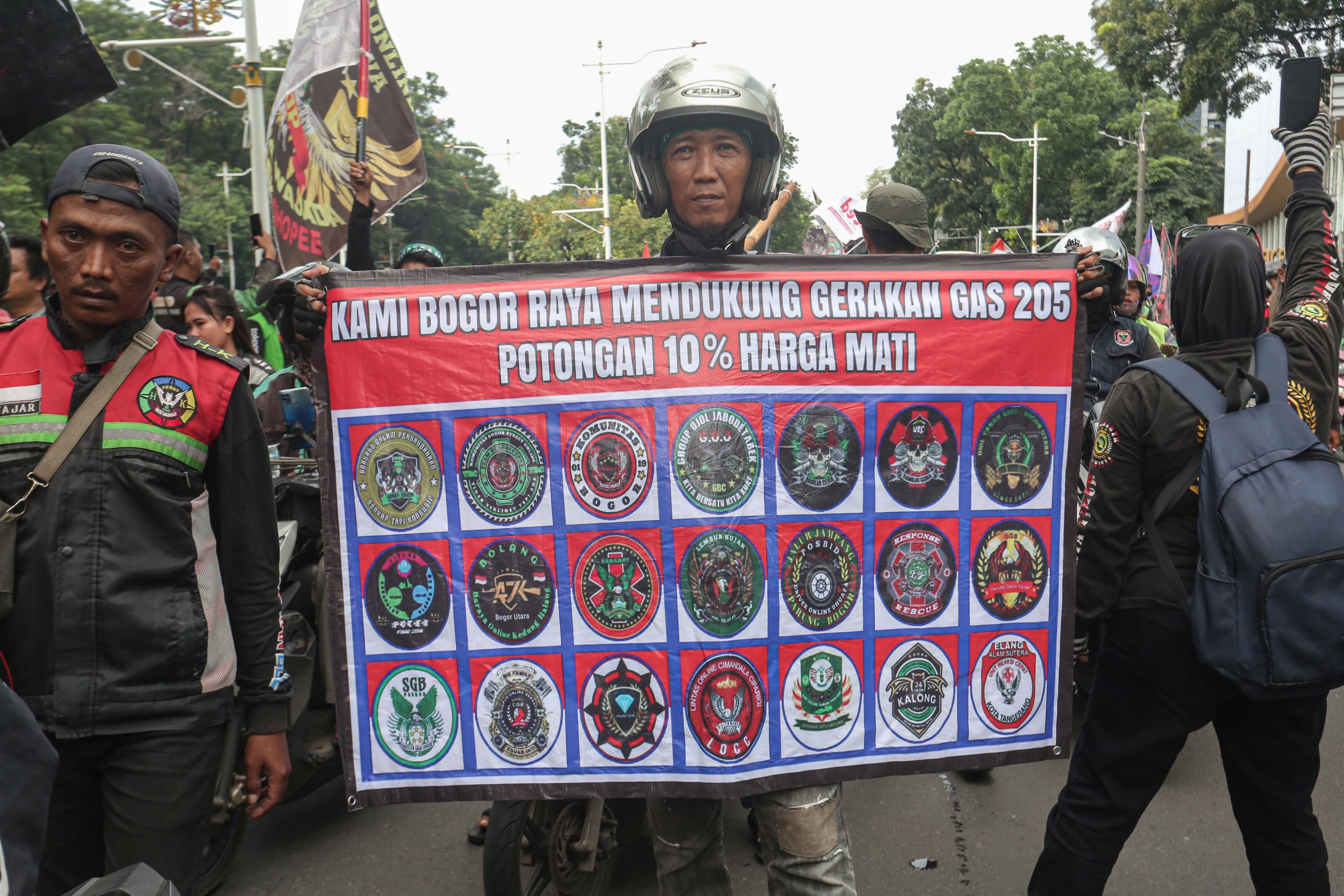 Seorang pengemudi ojek online (ojol) membentangkan spanduk tuntutan saat melakukan aksi demonstrasi di kawasan Patung Kuda, Monas, Jakarta Pusat, Selasa (20/5/2025). Dalam aksi ini mereka mendesak pemerintah agar memberikan sanksi tegas kepada perusahaan aplikasi yang melanggar peraturan batas maksimal potongan aplikator sebesar 20% dan menuntut agar potongan tersebut diturunkan menjadi 10% karena ketentuan sebelumnya dinilai memberatkan bagi pengemudi ojol.