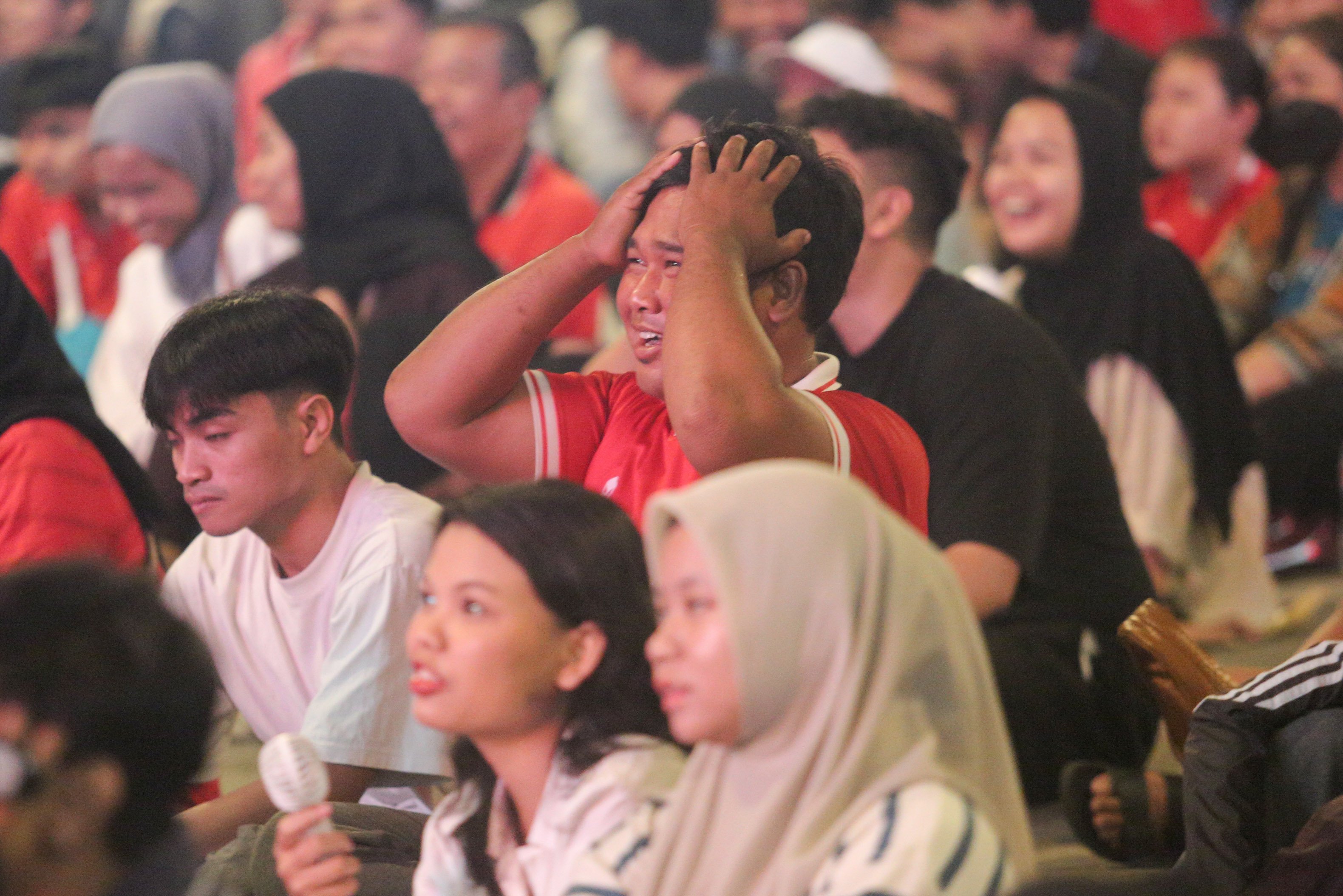 Ekspresi seorang warga saat menyaksikan pertandingan Grup C Putaran Ketiga Kualifikasi Piala Dunia 2026 Zona Asia antara Timnas Indonesia melawan Jepang melalui videotron di kawasan Stadion Utama Gelora Bung Karno, Jakarta, Selasa (10/6/2025). Nonton bareng tersebut digelar untuk memberikan dukungan kepada Timnas Indonesia.