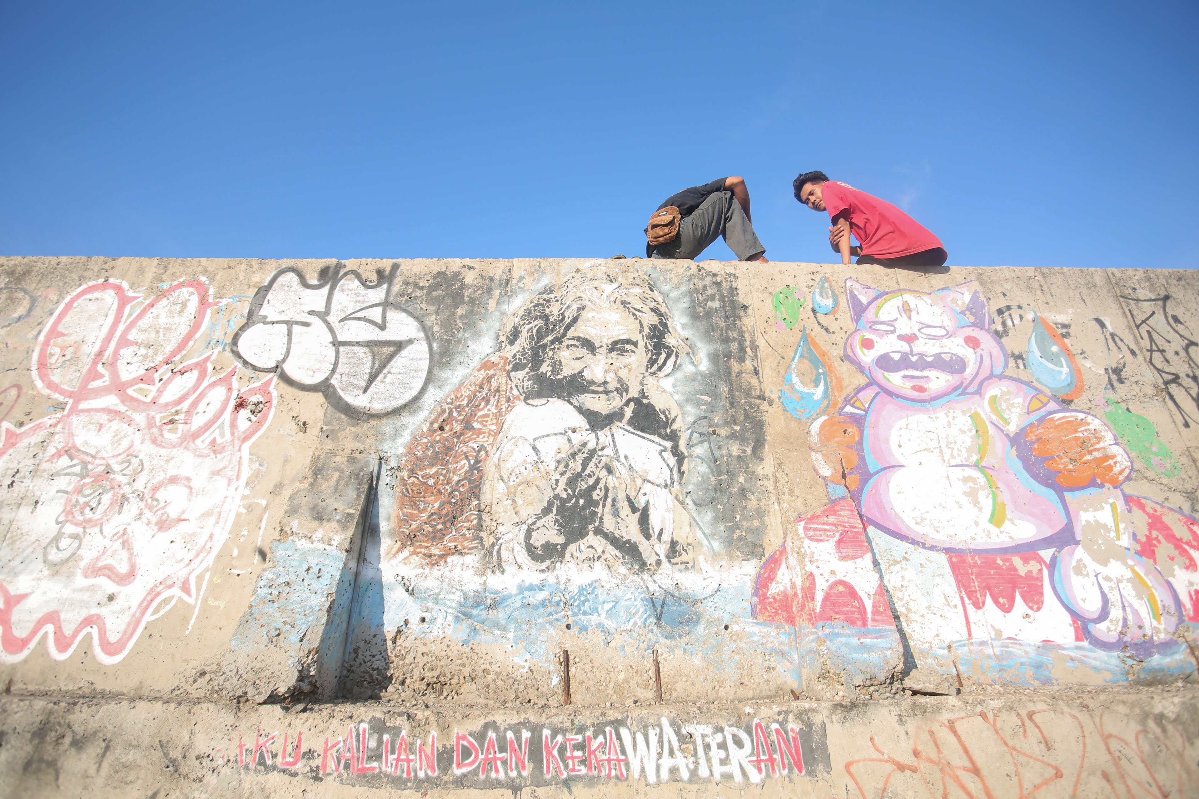 Warga duduk di atas tanggul laut di kawasan Muara Baru, Penjaringan, Jakarta Utara, Senin (17/6/2025). Pemerintah Provinsi DKI Jakarta akan menggunakan surplus Anggaran Pendapatan dan Belanja Daerah (APBD) dan pendapatan dari pengolahan sampah menjadi energi listrik untuk membiayai pembangunan Giant Sea Wall atau tanggul laut raksasa.