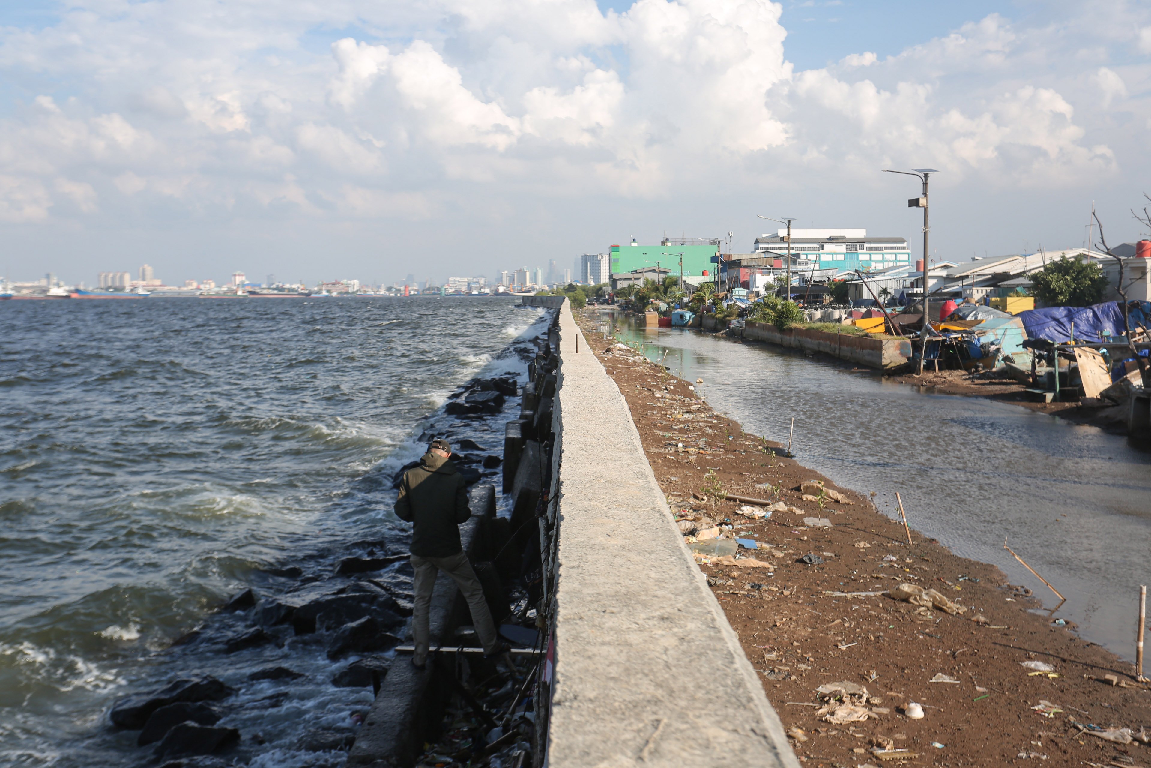 Warga berada di dekat tanggul laut di kawasan Muara Baru, Penjaringan, Jakarta Utara, Senin (17/6/2025). Pemerintah Provinsi DKI Jakarta akan menggunakan surplus Anggaran Pendapatan dan Belanja Daerah (APBD) dan pendapatan dari pengolahan sampah menjadi energi listrik untuk membiayai pembangunan Giant Sea Wall atau tanggul laut raksasa. 