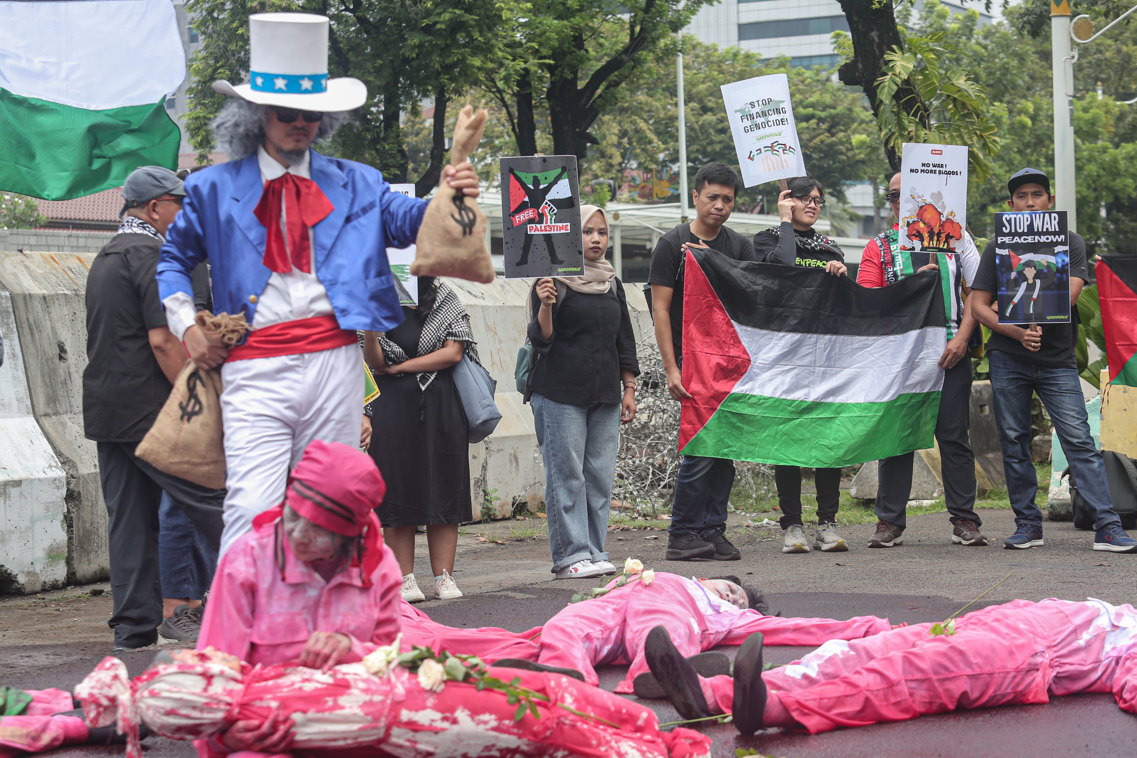 Aktivis Greenpeace Indonesia melakukan aksi teatrikal saat menggelar aksi solidaritas untuk masyarakat Gaza di depan Kedutaan Besar Amerika Serikat, Jakarta, Kamis (19/6/2025). Dalam aksinya tersebut mereka menyerukan kepada semua pihak termasuk pemerintah Amerika Serikat untuk bekerja sama dalam upaya menghentikan genosida di Palestina yang dilakukan oleh Israel.
