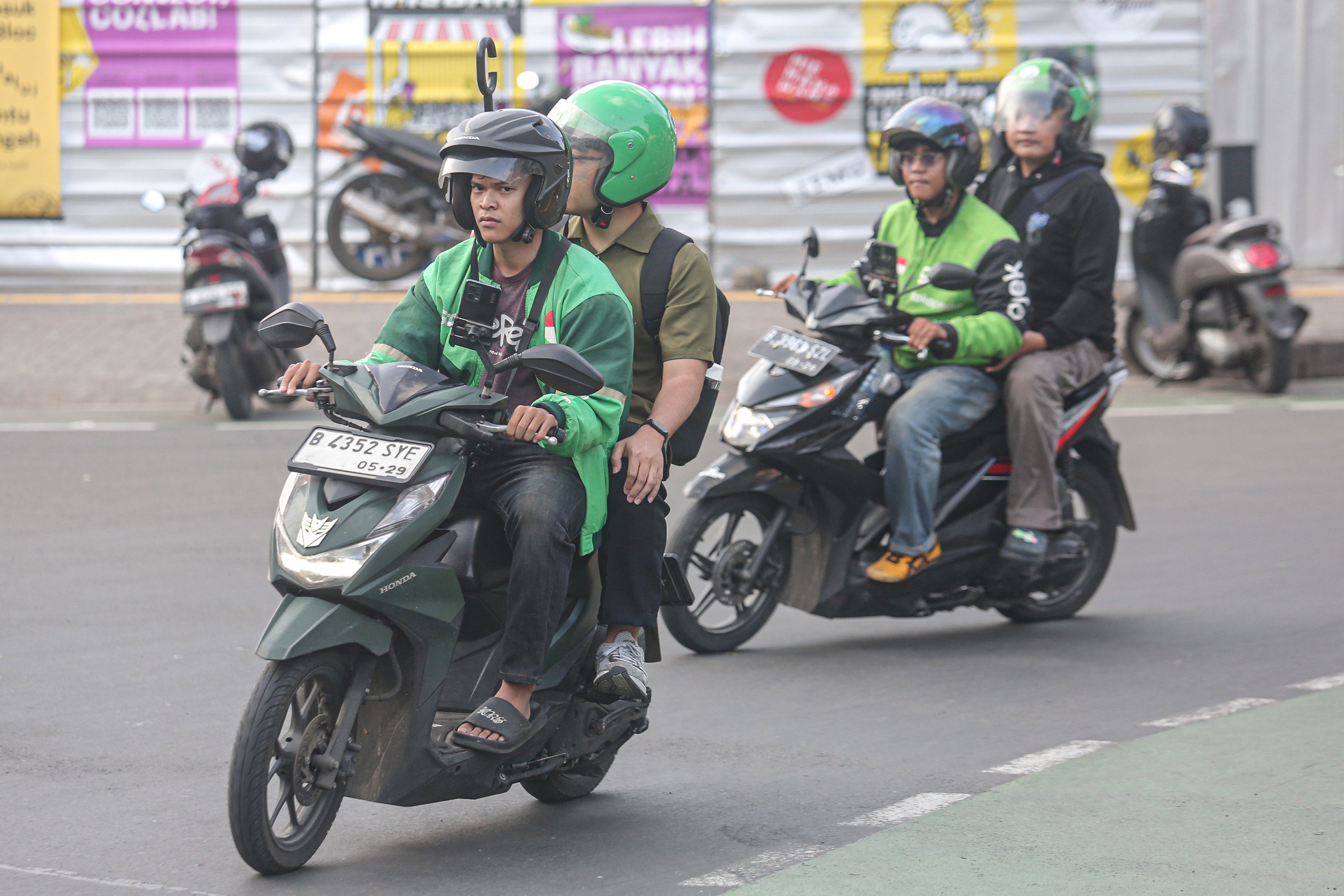 Dua pengemudi ojek online (ojol) membawa penumpang di Jalan Panglima Polim, Blok M, Jakarta, Kamis (3/7/2025). Kementerian Perhubungan (Kemenhub) tengah mengkaji kenaikan tarif ojol sebesar 8%-15% dengan jumlah eskalasi yang bervariasi tergantung zona wilayah masing-masing pengguna.