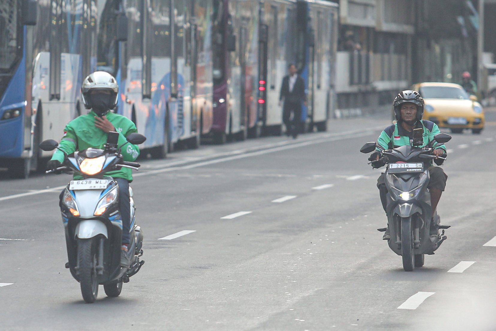 Dua pengemudi ojek online (ojol) melintas di Jalan Panglima Polim, Blok M, Jakarta, Kamis (3/7/2025). Kementerian Perhubungan (Kemenhub) tengah mengkaji kenaikan tarif ojol sebesar 8%-15% dengan jumlah eskalasi yang bervariasi tergantung zona wilayah masing-masing pengguna.