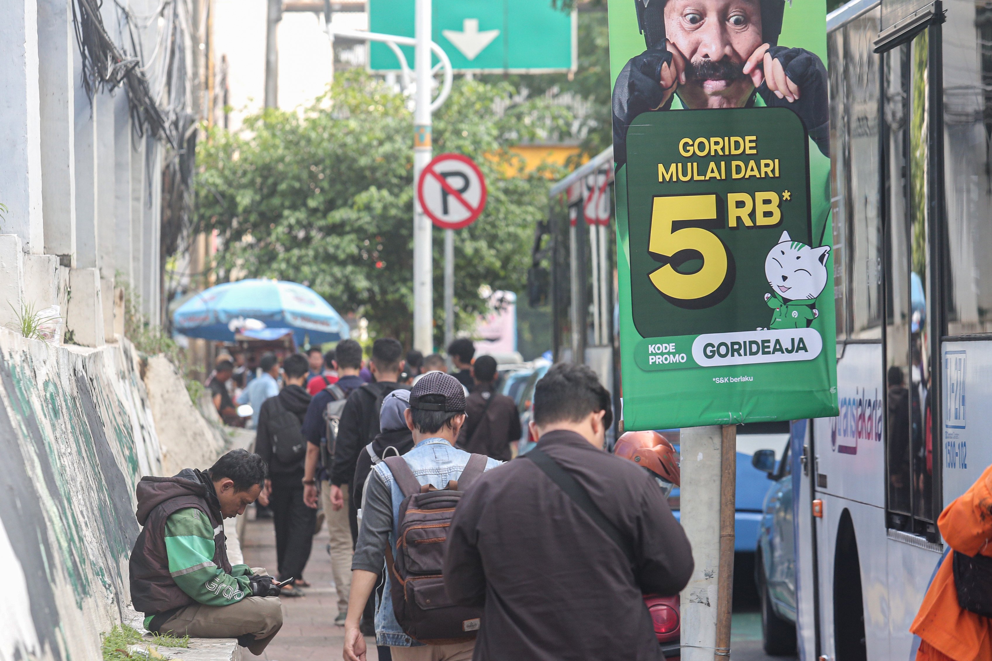 Seorang pengemudi ojek online (kiri) menunggu orderan di kawasan Palmerah, Jakarta, Kamis (3/7/2025). Kementerian Perhubungan (Kemenhub) tengah mengkaji kenaikan tarif ojol sebesar 8%-15% dengan jumlah eskalasi yang bervariasi tergantung zona wilayah masing-masing pengguna.