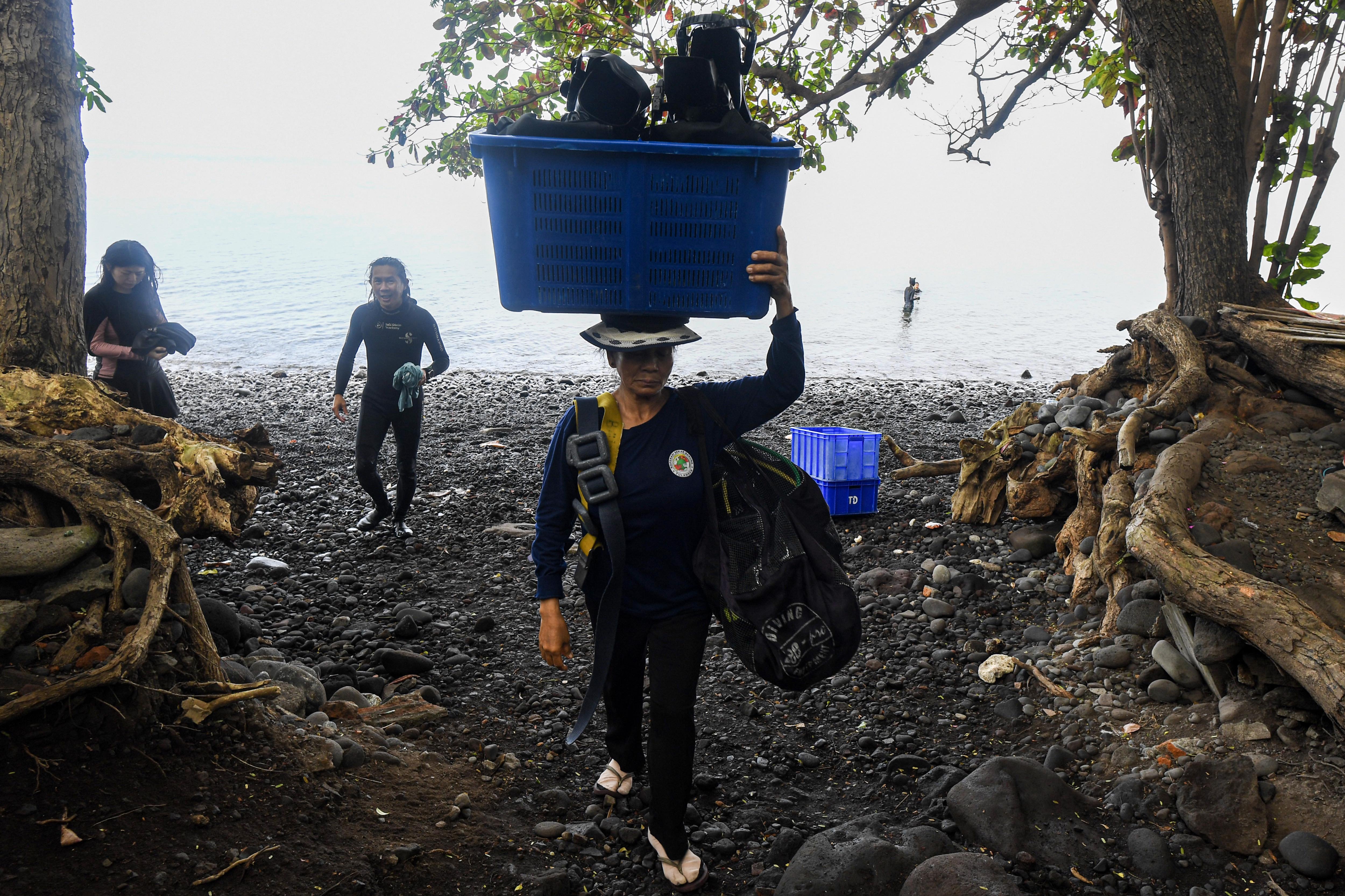 Seorang porter membawakan alat selam milik wisatawan di Desa Tulamben, Kubu, Karangasem, Bali.