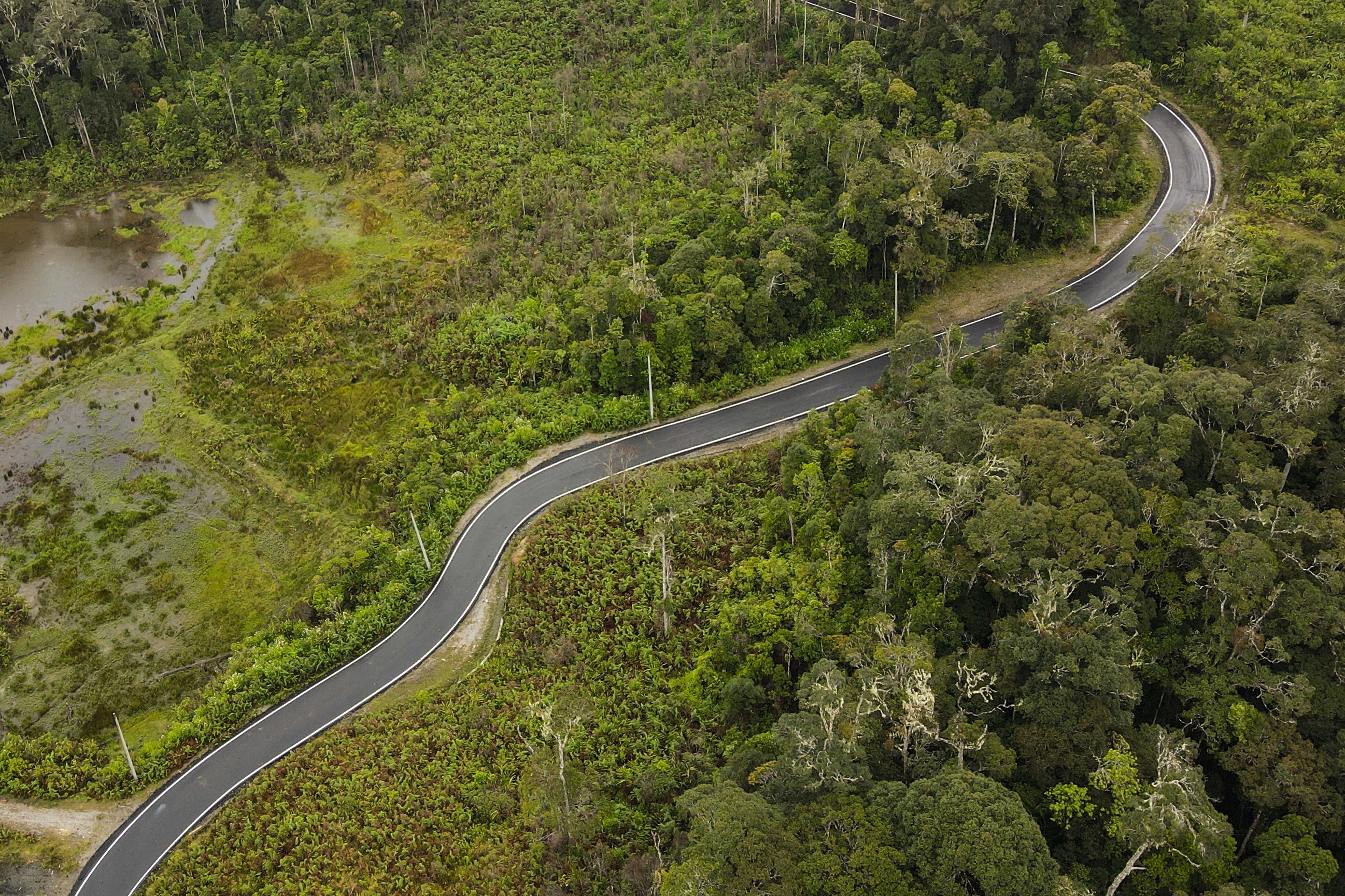 Foto udara jalan poros Sabbang-Seko yang sudah diaspal dengan deretan tiang listrik terpancang di sisinya di Luwu Utara, Sulawesi Selatan.